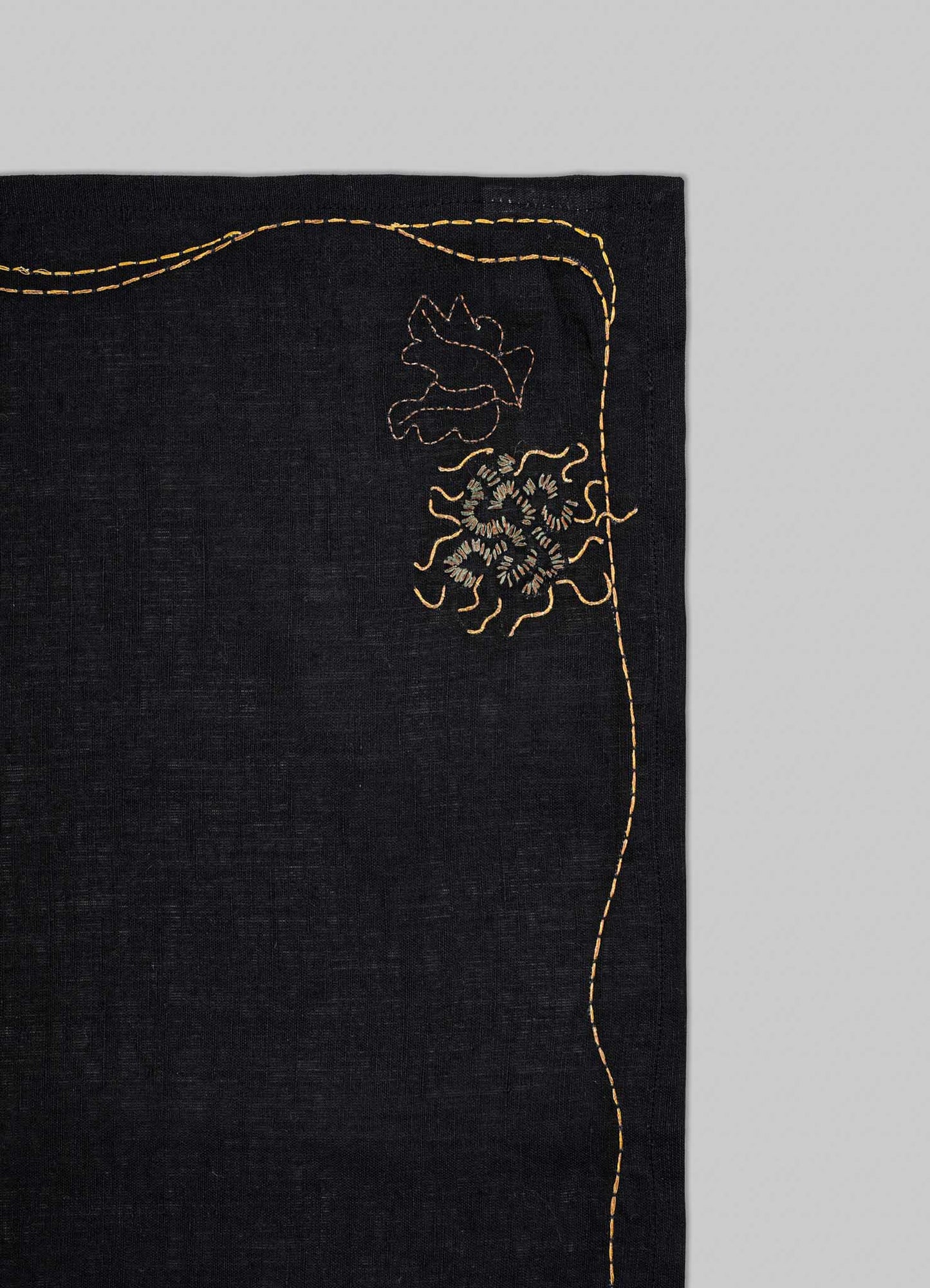 Black fabric with gold embroidery on a gray background viya luxury placemats