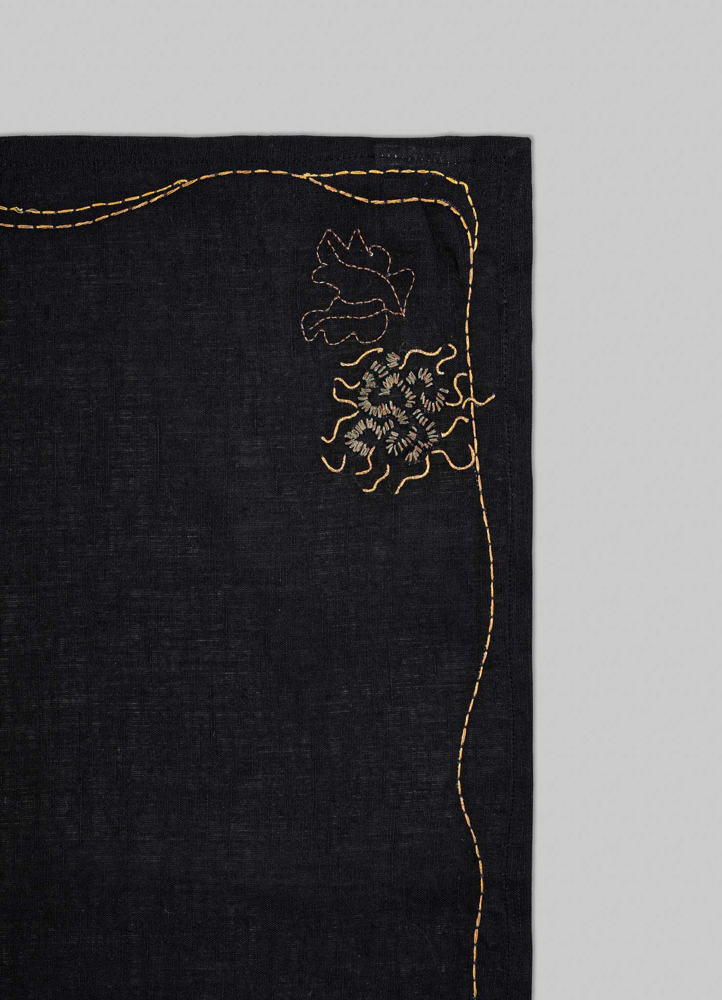 Black fabric with gold embroidery on a gray background viya luxury placemats