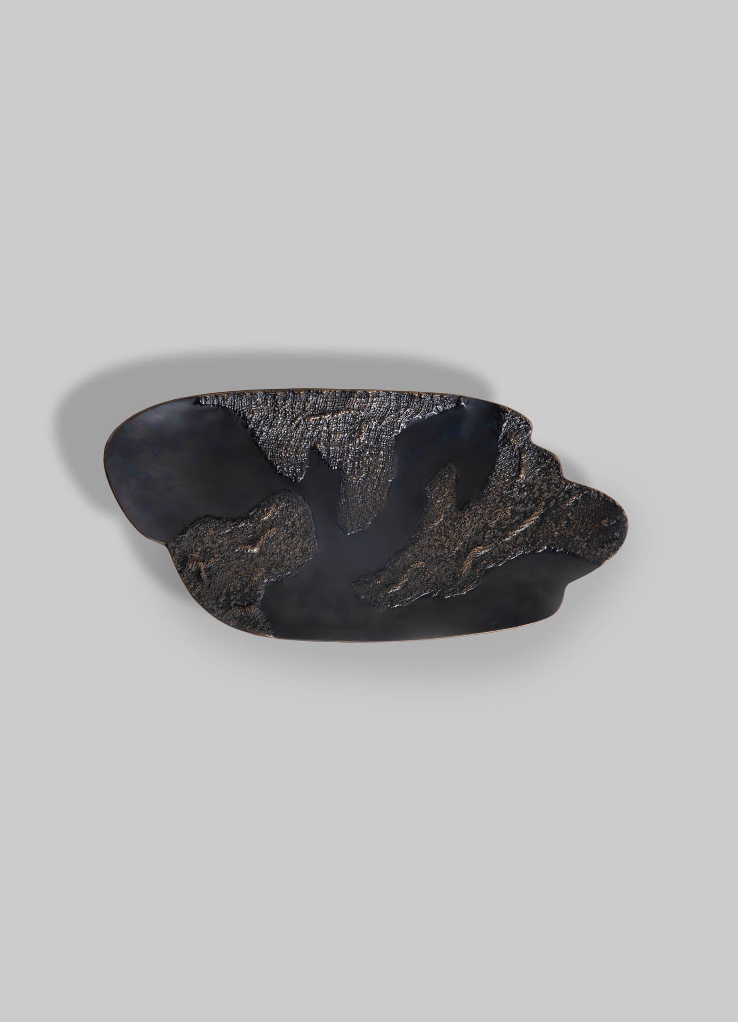 Black ceramic bowl with a matte finish and abstract textured pattern, featuring organic, fluid shapes and a subtly uneven edge.