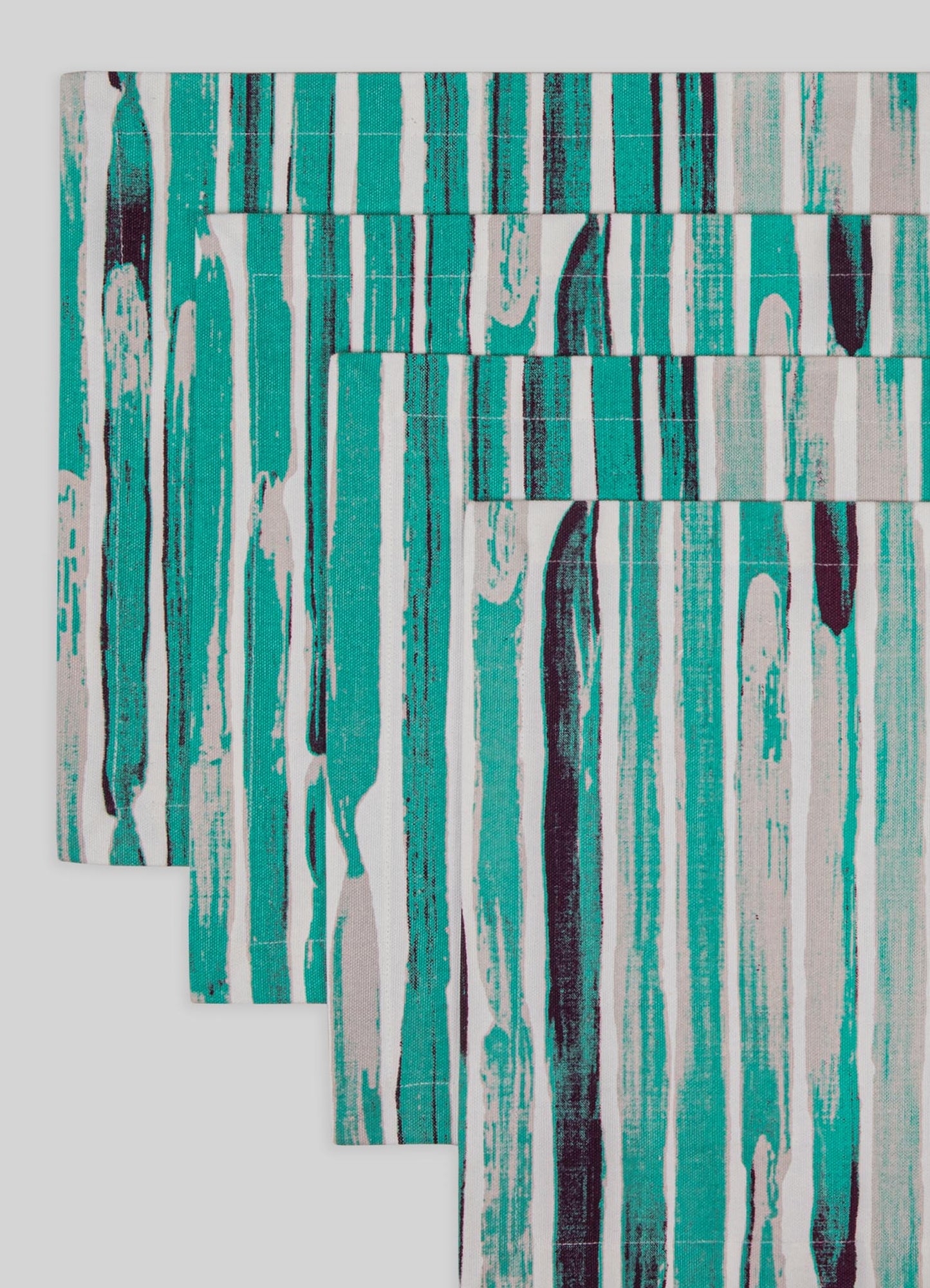 Printed table linen set with an abstract, vertical stripe pattern in shades of teal, black, and white, made from woven fabric. The design features irregular, painterly motifs with a contemporary and artisanal style.