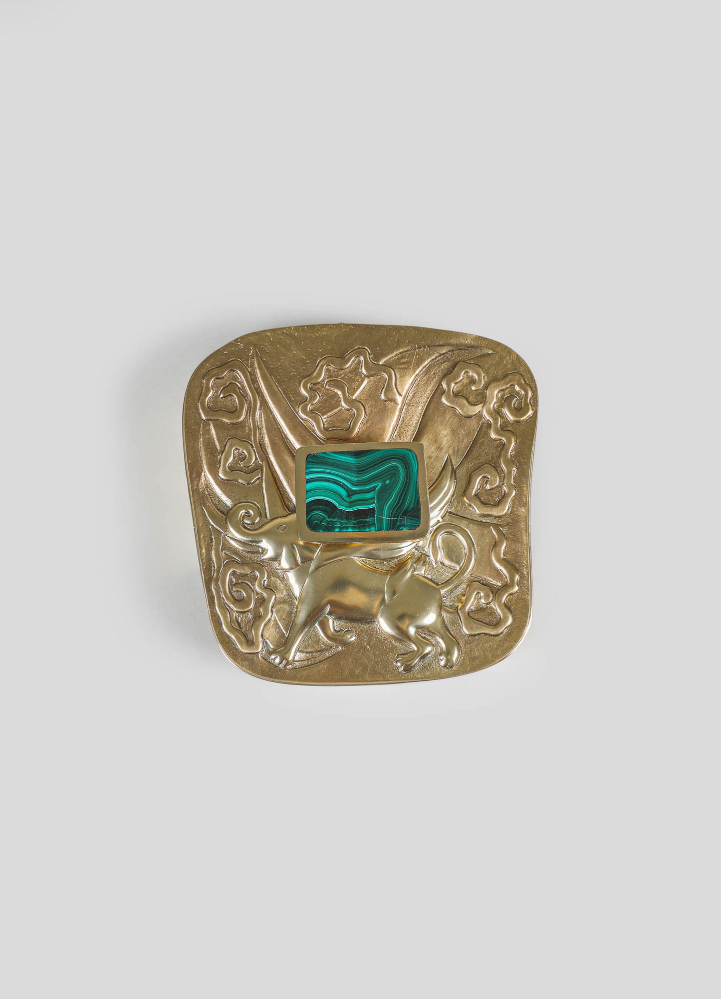 A decorative brass brooch with engraved floral and animal motifs, featuring a rectangular malachite stone inset in the center.
