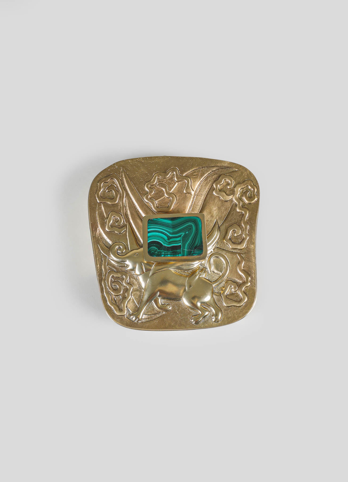 A decorative brass brooch with engraved floral and animal motifs, featuring a rectangular malachite stone inset in the center.