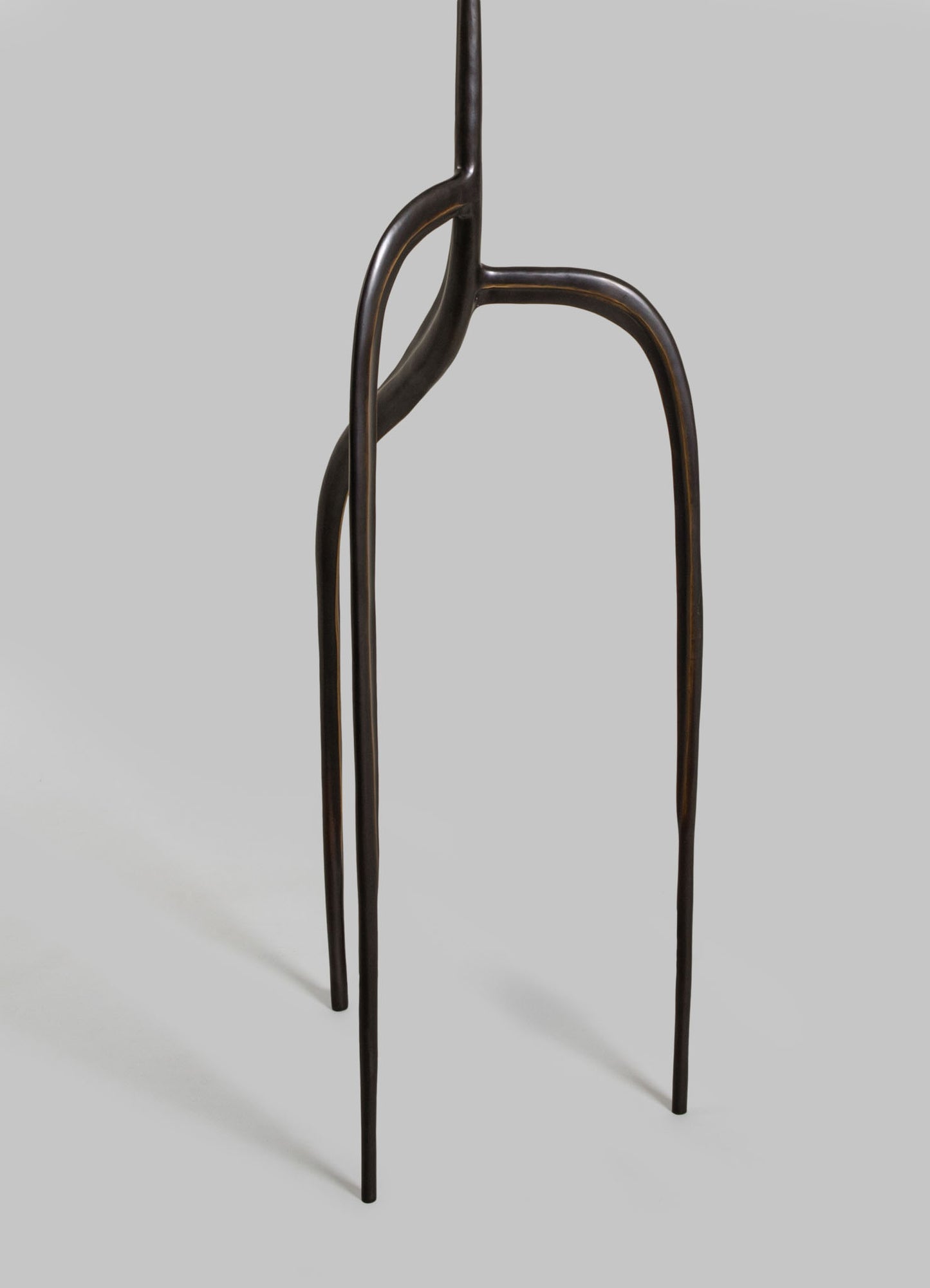 A sculptural furniture piece with a dark, polished wooden finish featuring curved, elongated legs and an organic, asymmetrical design. The piece has a contemporary style with a natural, handcrafted aesthetic.