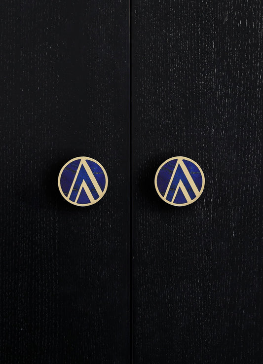 Black wooden surface with a textured finish, featuring two round handles with blue and gold geometric pattern and metallic gold edges.