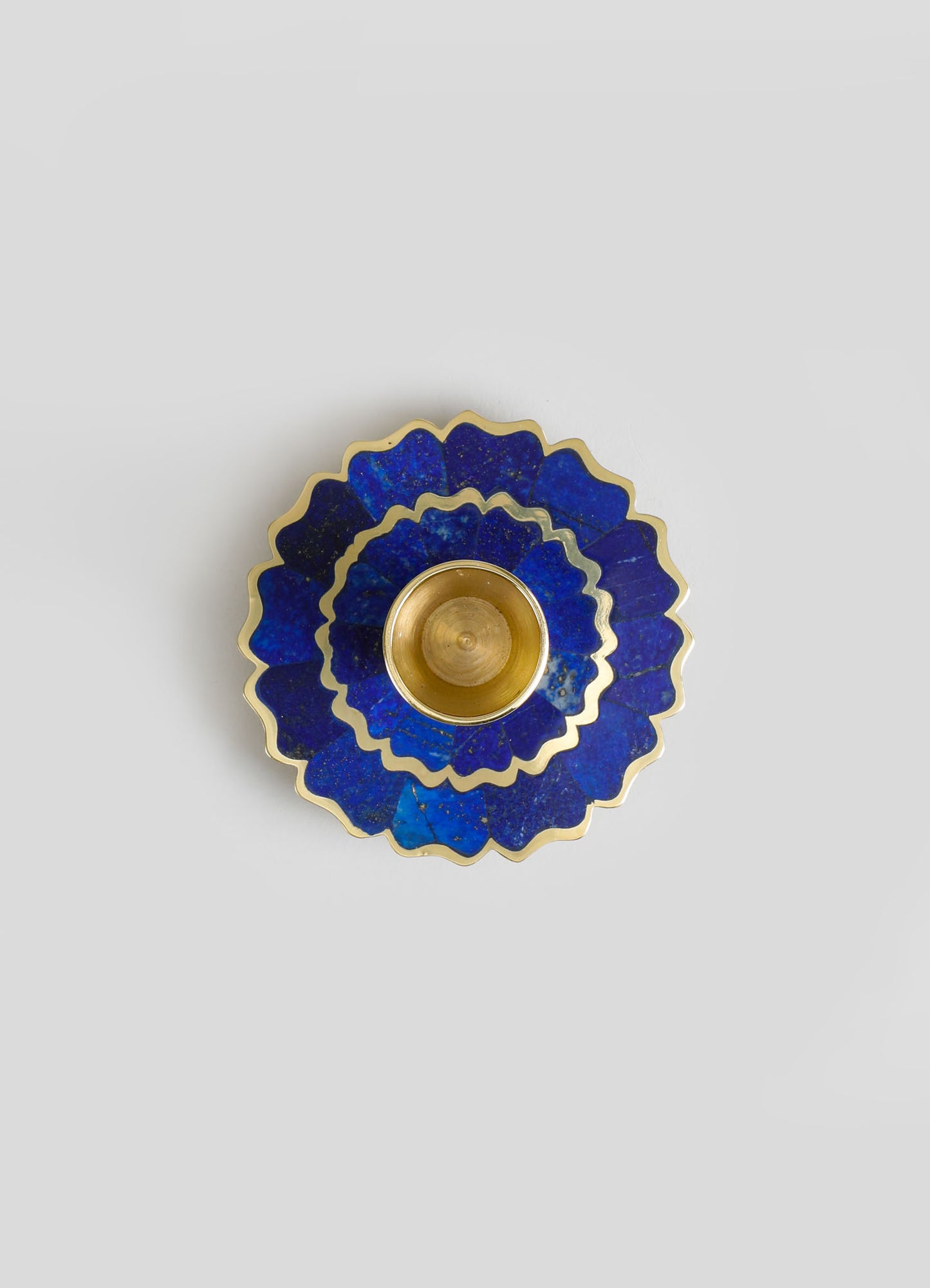 A decorative ceramic tray with scalloped edges and a deep blue glaze with gold accents, stacked beneath a small golden bowl.