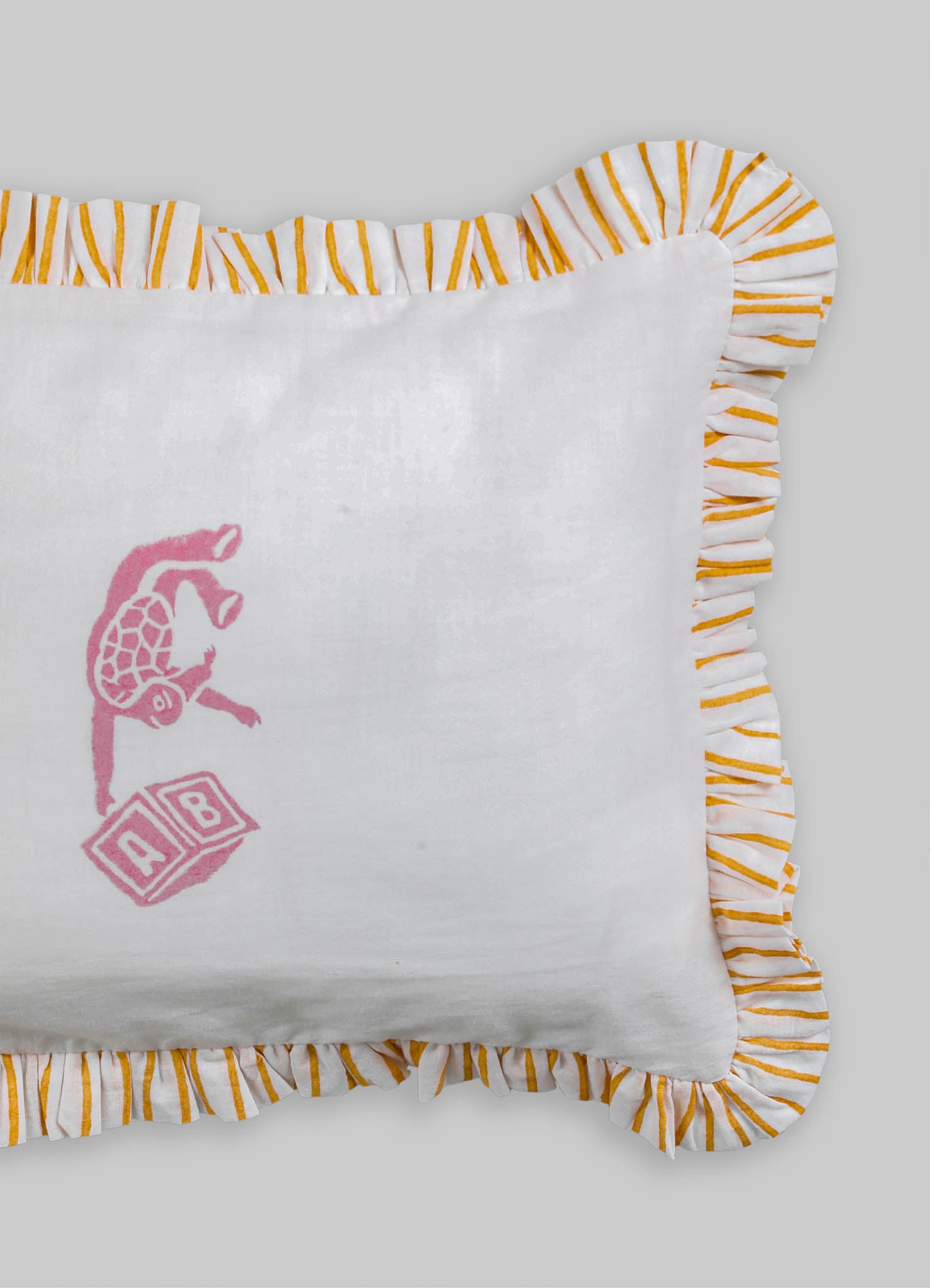 White fabric cushion with embroidered pink design and a ruffled border featuring orange and white striped fabric.