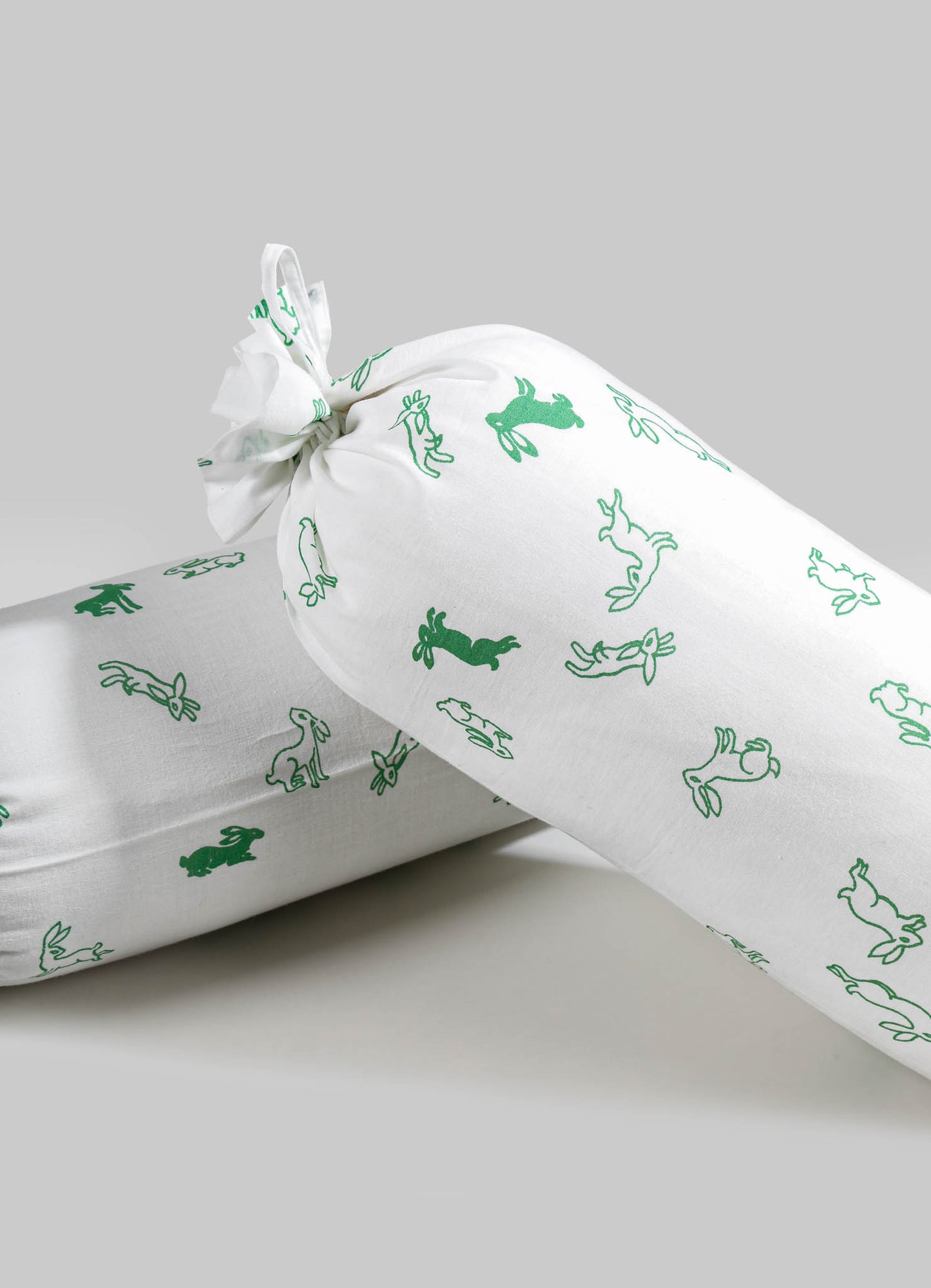 White fabric wrapping with a green animal and rabbit motif print, tied at the top with a fabric tie. The material appears to be cotton or similar soft textile, featuring a playful pattern suitable for gift wrapping or packaging.
