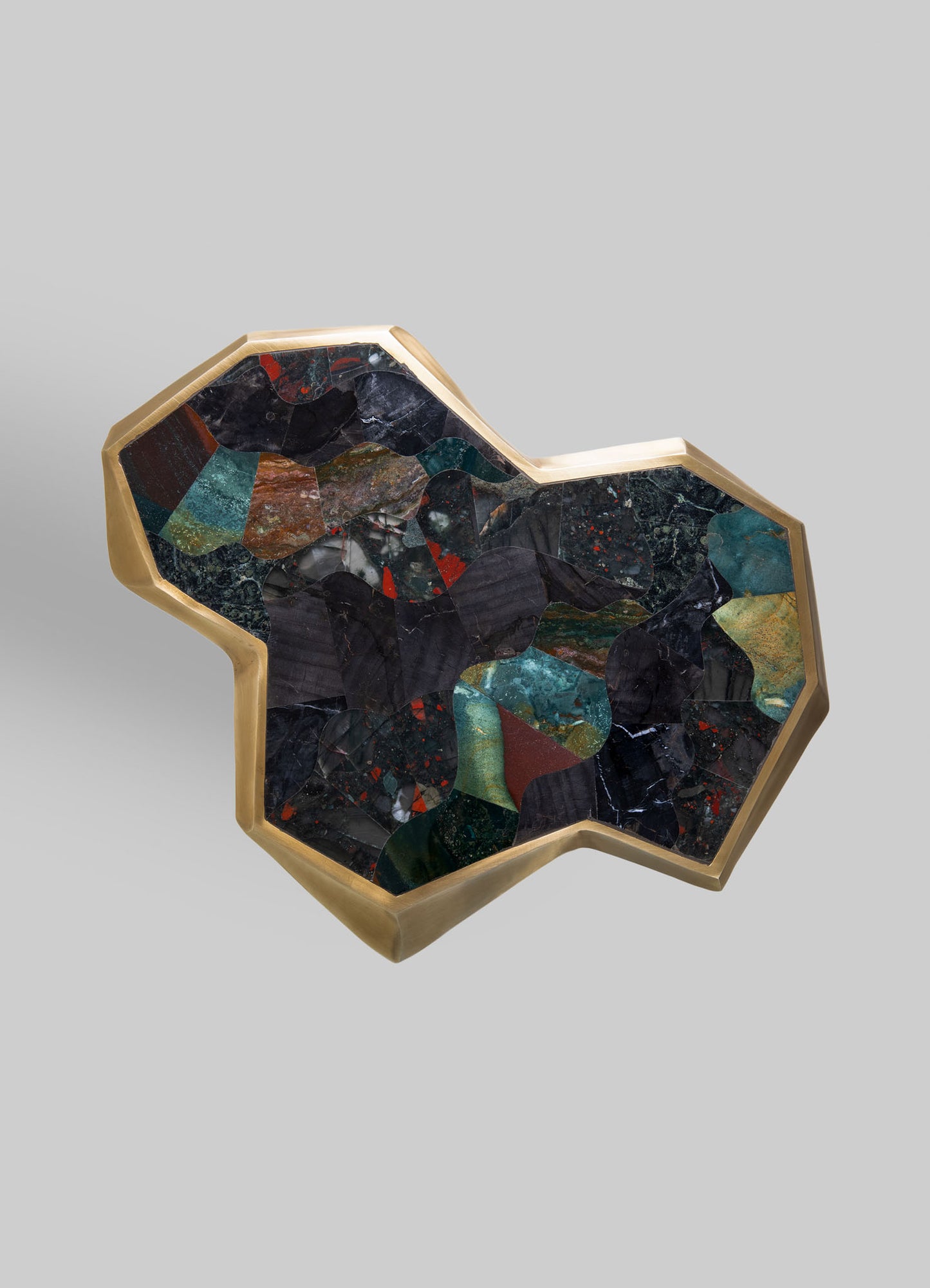 A decorative tray featuring a brass frame with an irregular geometric shape, inlaid with multicolored stone or marble pieces arranged in an abstract pattern, creating a luxurious and artisanal appearance.