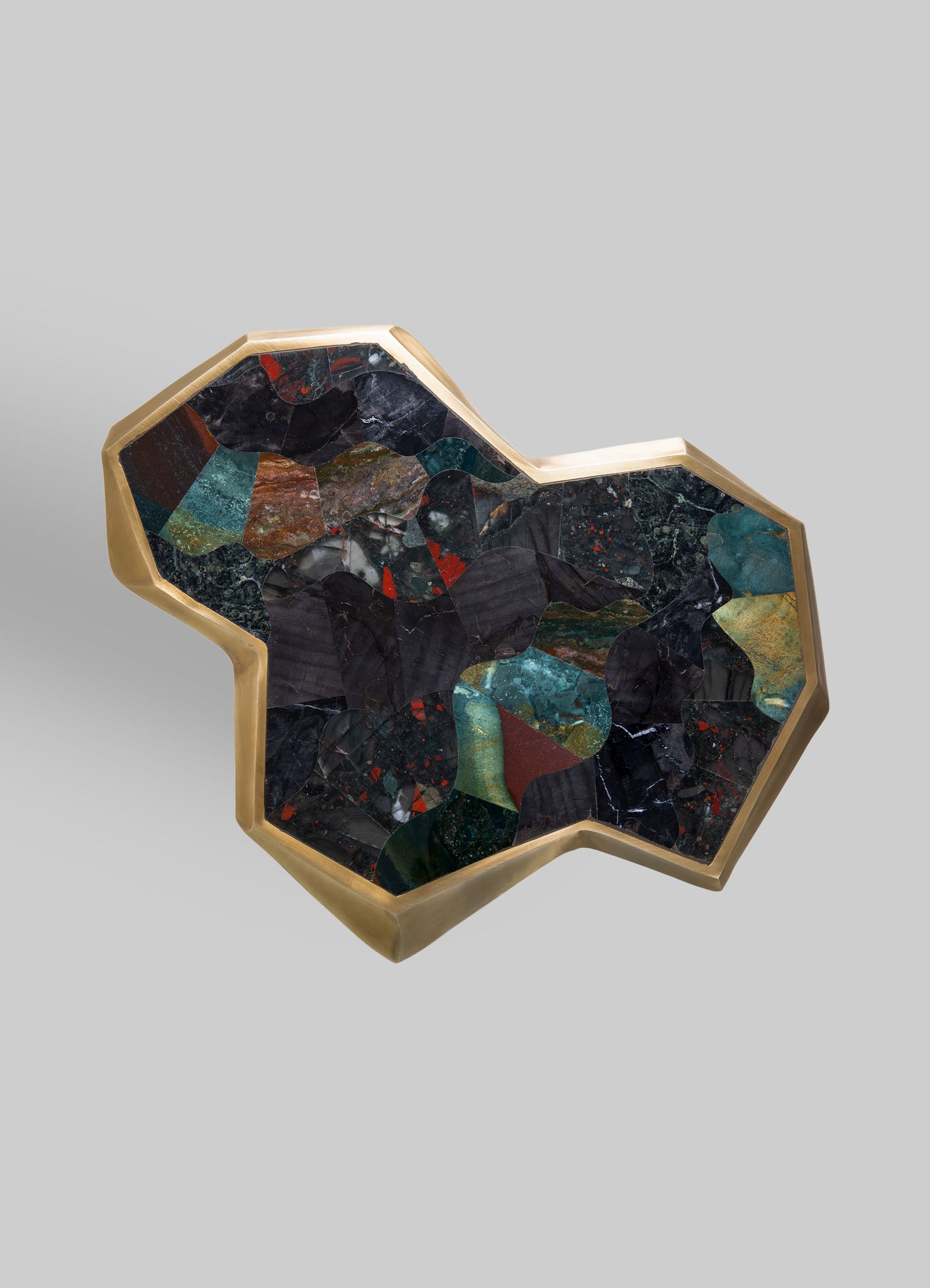 A decorative tray featuring a brass frame with an irregular geometric shape, inlaid with multicolored stone or marble pieces arranged in an abstract pattern, creating a luxurious and artisanal appearance.