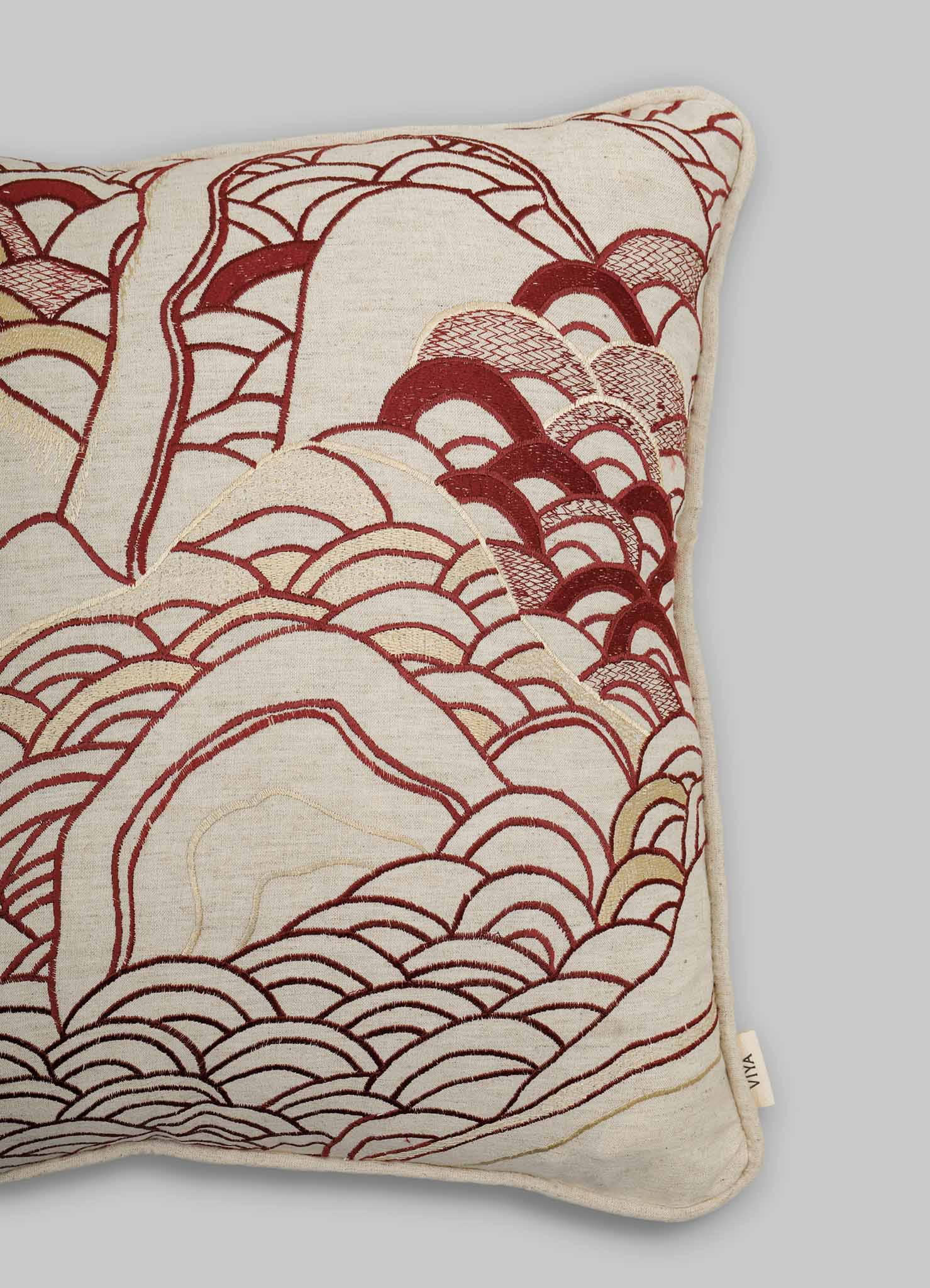 The Viya Dreamscape Red Embroidered Cushion Cover A (18"x18") features intricate maroon and gold wave patterns inspired by Japanese art on off-white fabric, displayed against a plain gray background.