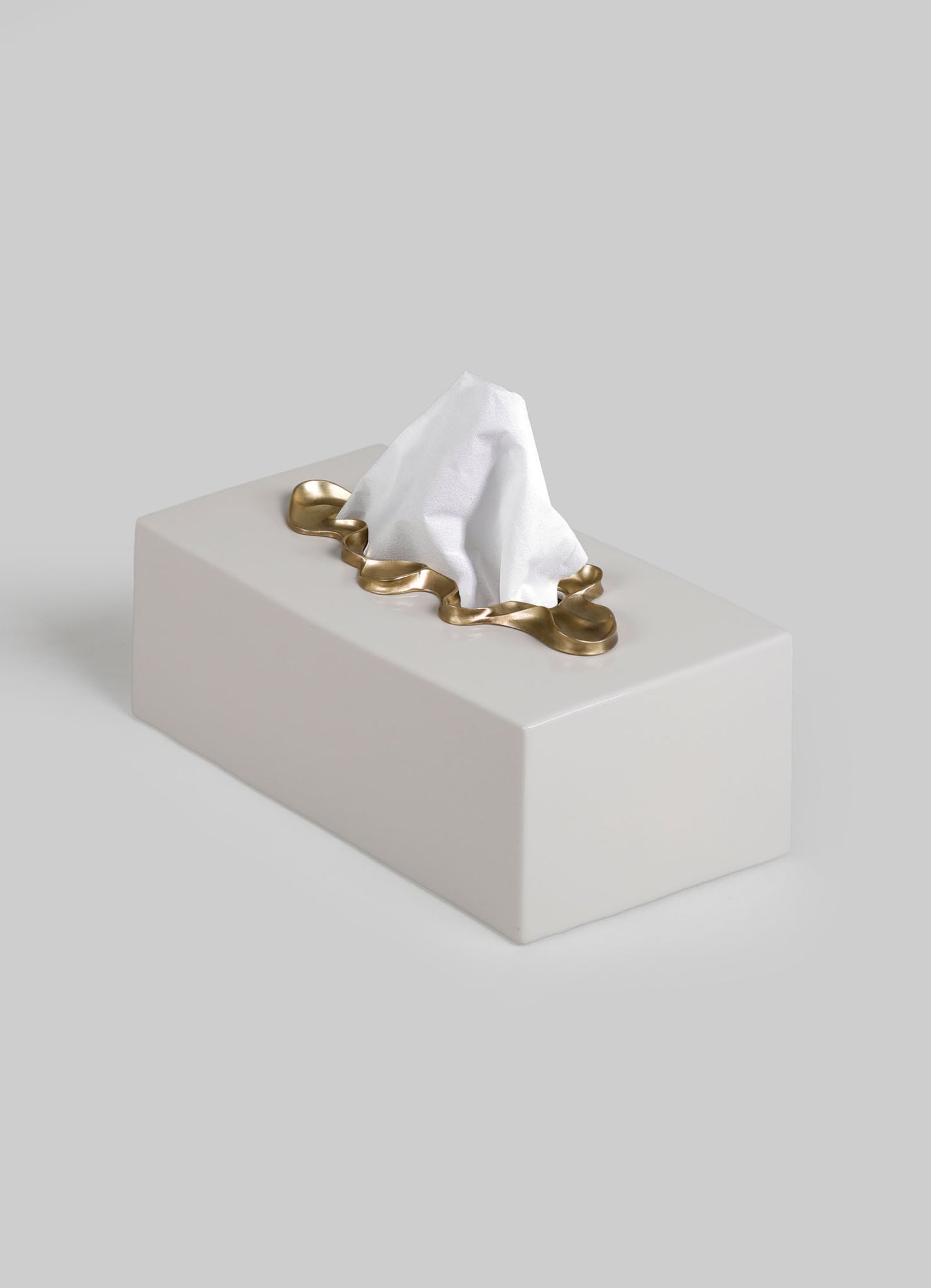 A ceramic tissue box holder with a rectangular shape, featuring a brass wavy border around the opening, against a light gray background.