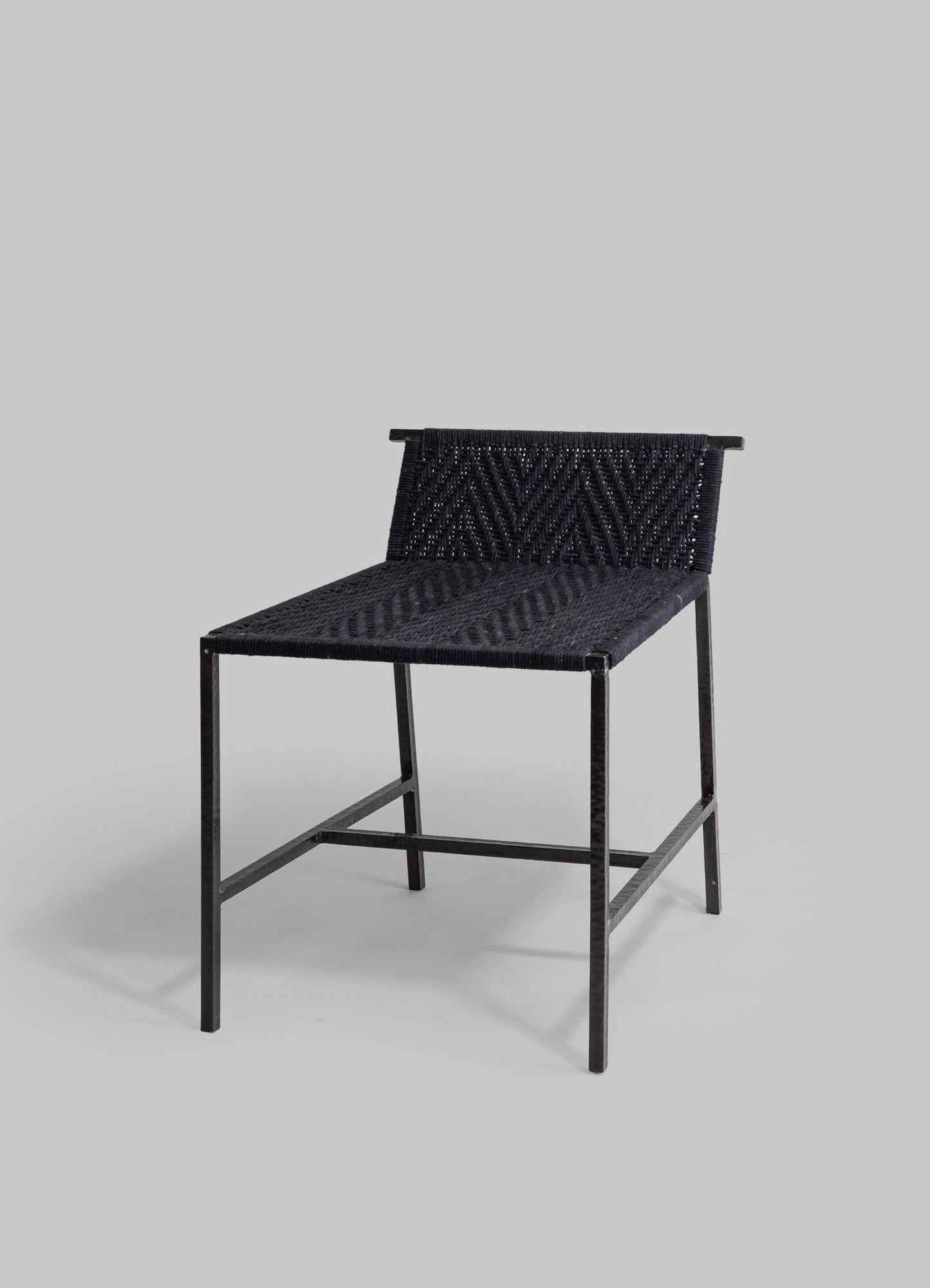 A black woven textile chair with a metal frame, featuring a chevron pattern on the backrest and seat, against a plain background.