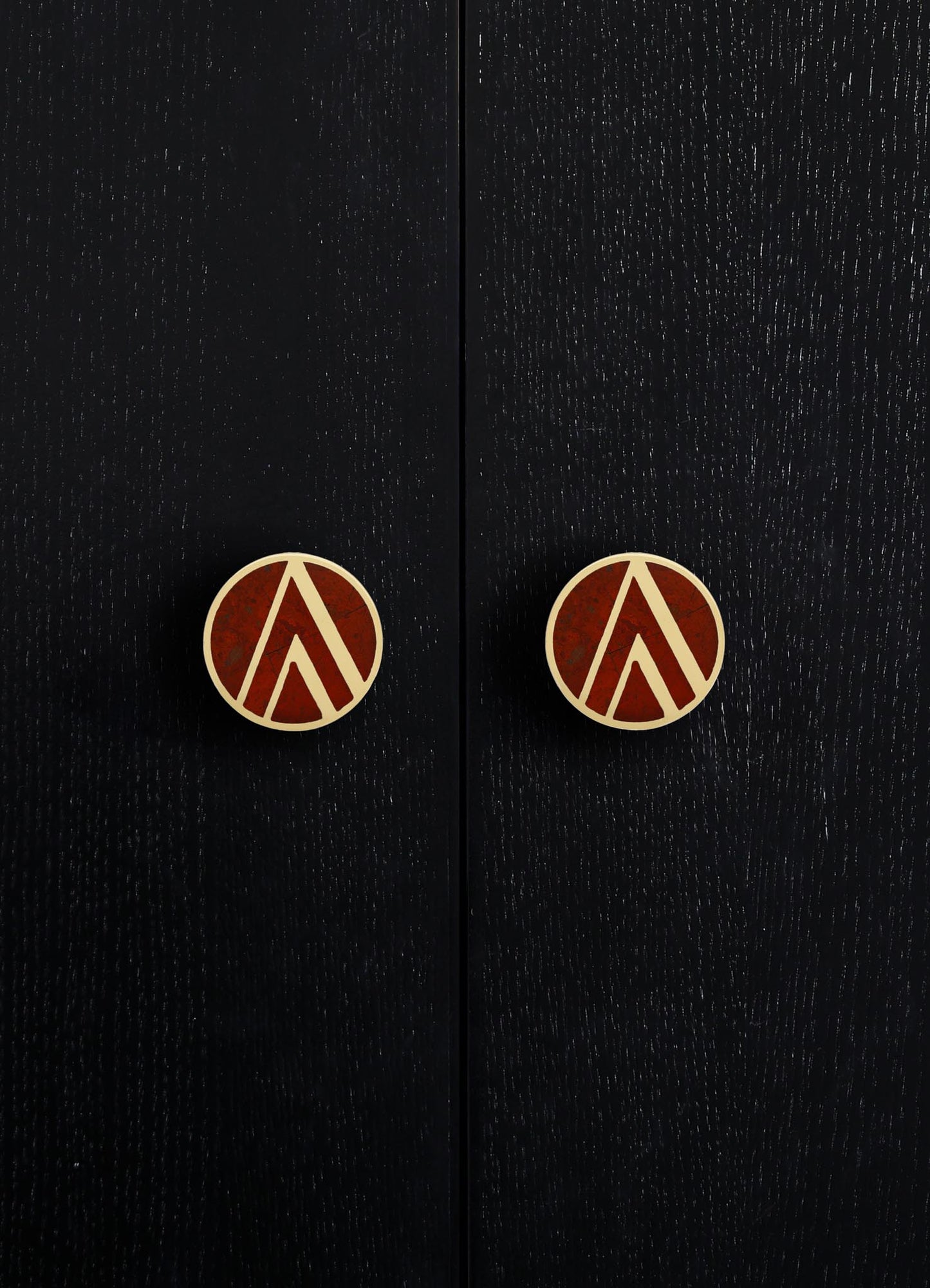 Black wooden cabinet with a textured finish and round brass knobs featuring geometric patterns in reddish-brown and brass tones. The style appears contemporary with a focus on sleek surface details and decorative hardware.