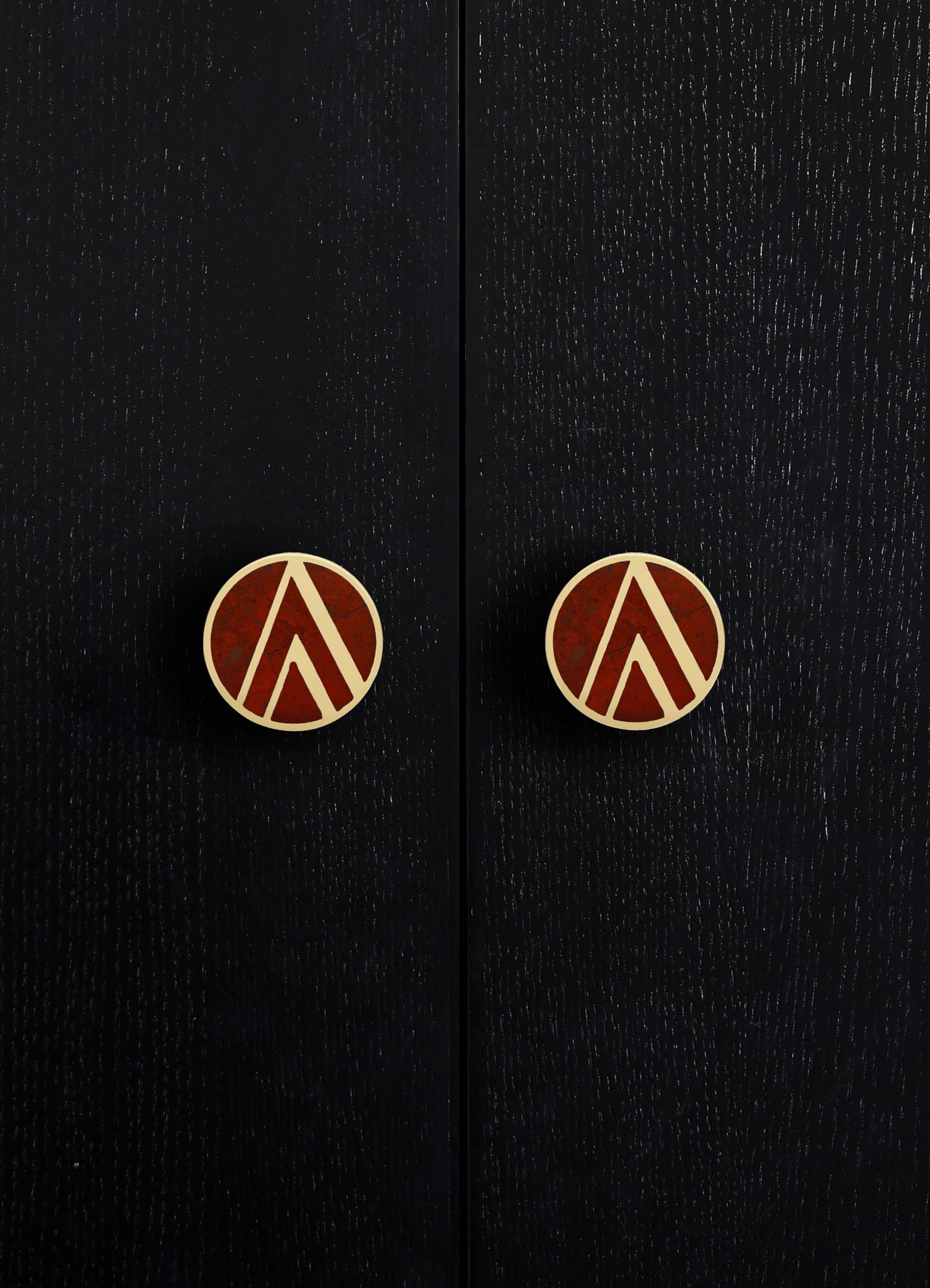 Black wooden cabinet with a textured finish and round brass knobs featuring geometric patterns in reddish-brown and brass tones. The style appears contemporary with a focus on sleek surface details and decorative hardware.