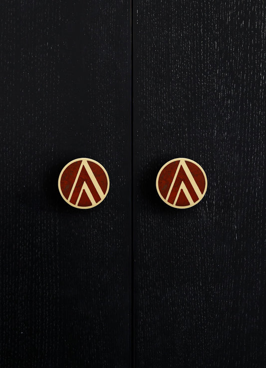 Black wooden cabinet with a textured finish and round brass knobs featuring geometric patterns in reddish-brown and brass tones. The style appears contemporary with a focus on sleek surface details and decorative hardware.