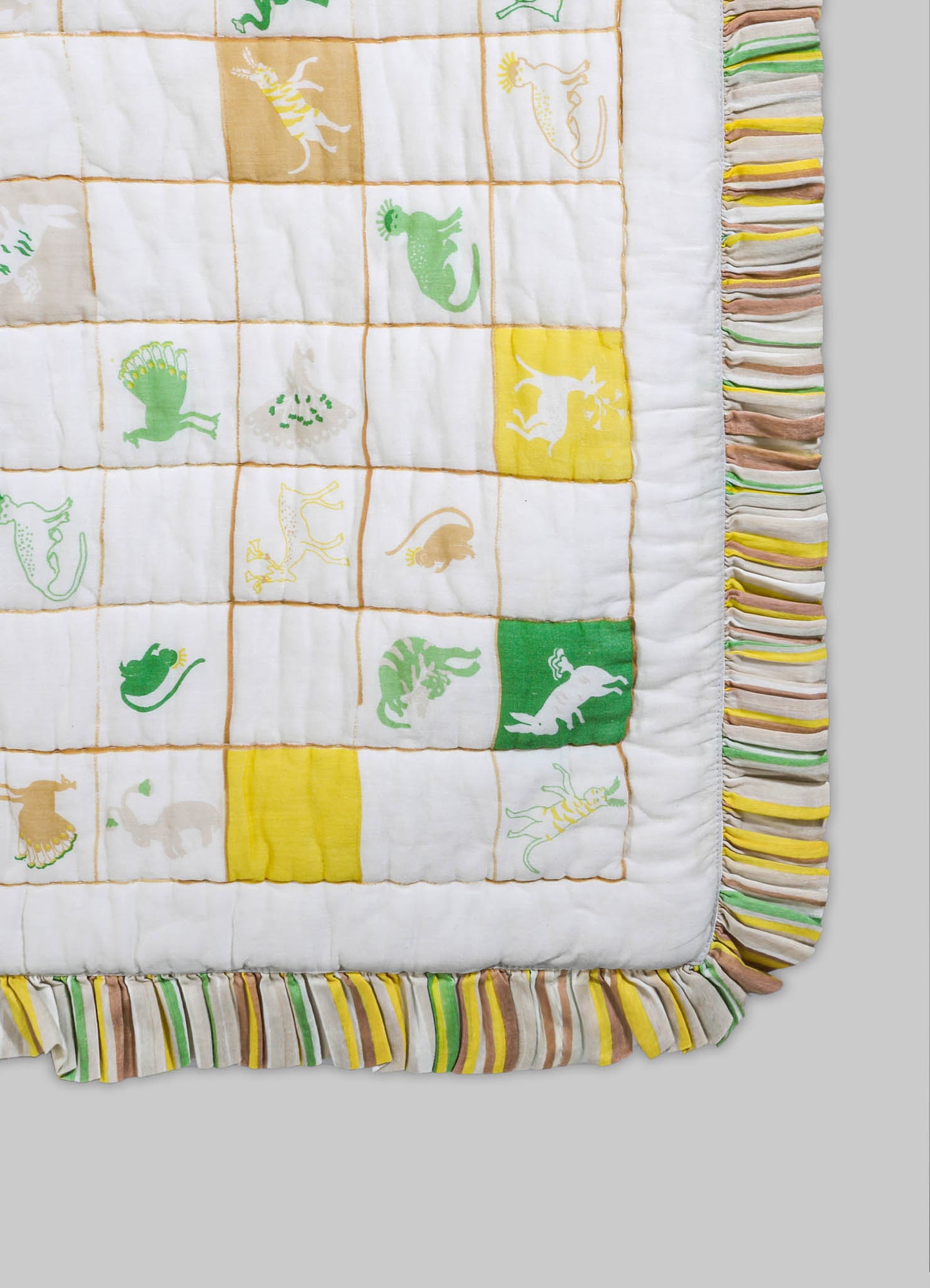 A quilt featuring colorful dinosaur motifs in shades of green, yellow, orange, and beige on a white fabric background, with a striped ruffled border in pastel colors.