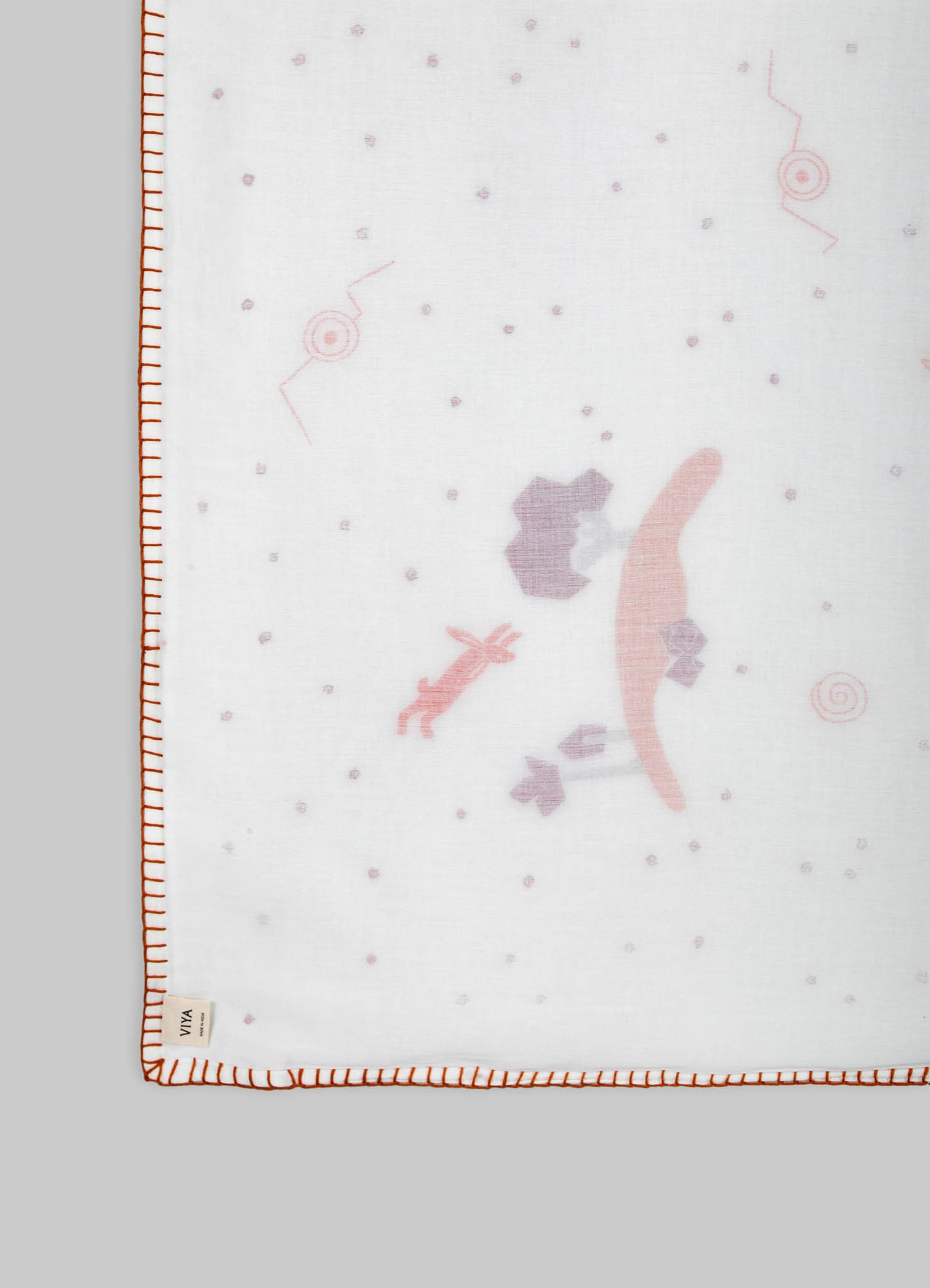 Cotton or linen fabric with subtle printed motifs and contrasting orange stitched border, likely a tablecloth or placemat, featuring a minimalist design and soft pastel hues.