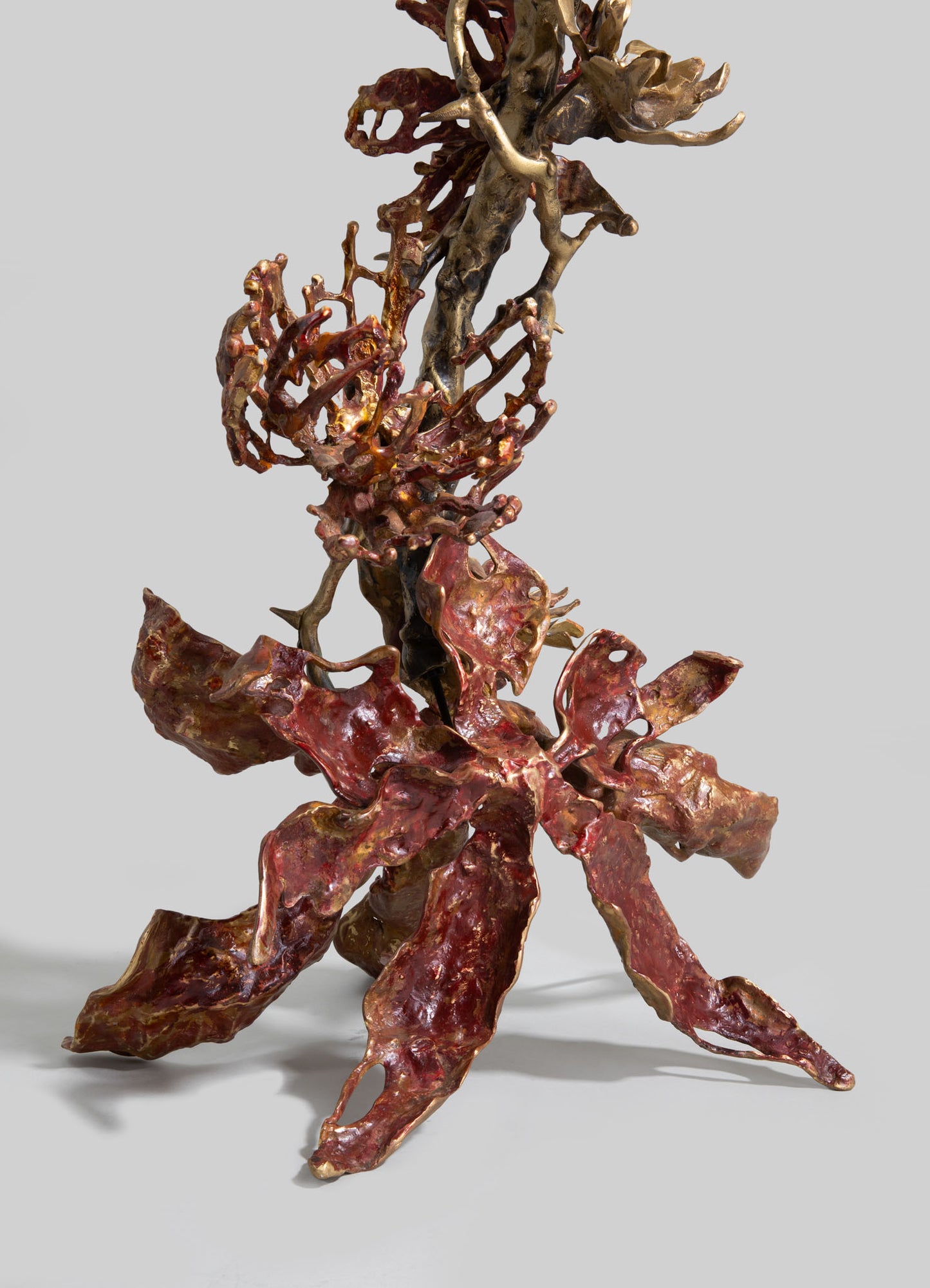 Bronze sculptural art piece featuring intricate, organic shapes with a polished, reddish-brown finish, set against a neutral background. The sculpture has a handcrafted appearance with flowing, natural motifs.