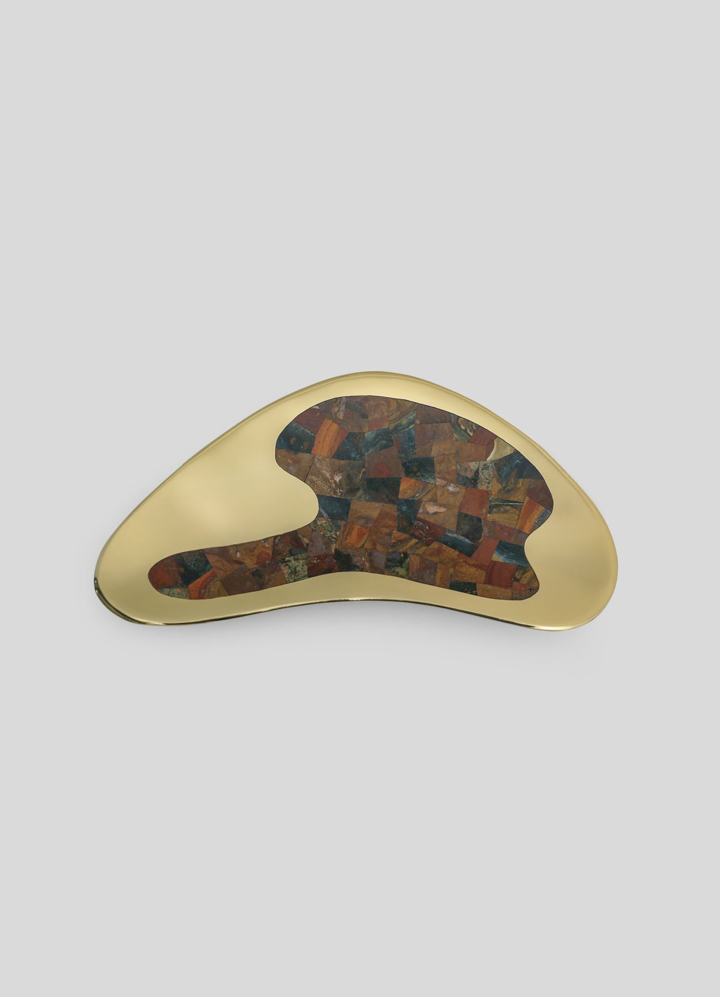 A decorative tray with an asymmetrical, organic shape featuring a polished gold finish and a mosaic pattern of multicolored stone inlays.