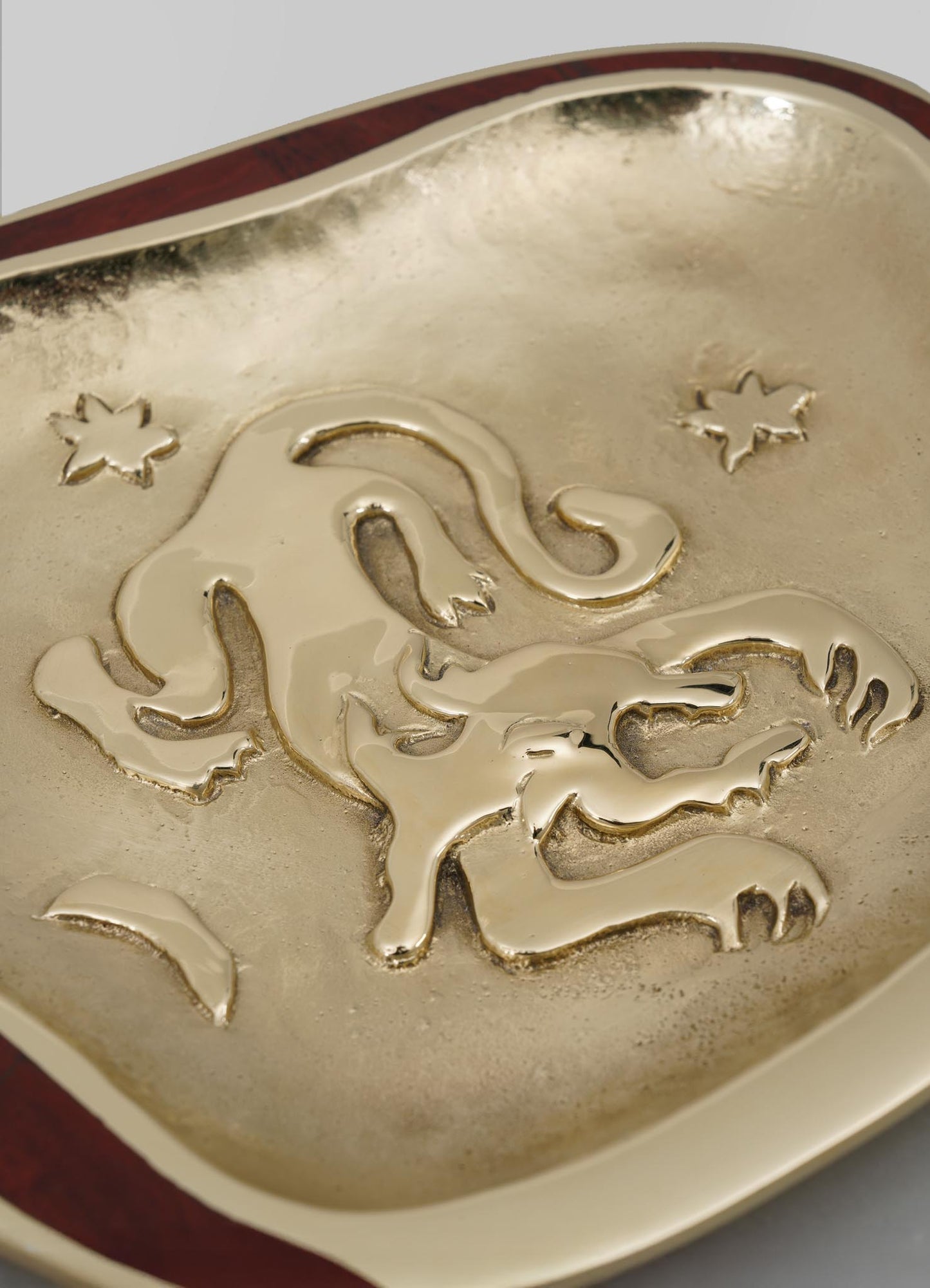 A decorative tray featuring a metallic gold finish with embossed lion motifs and engraved floral patterns, edged with a darker wood frame. The design combines regal and ornate elements with a luxurious, handcrafted aesthetic.