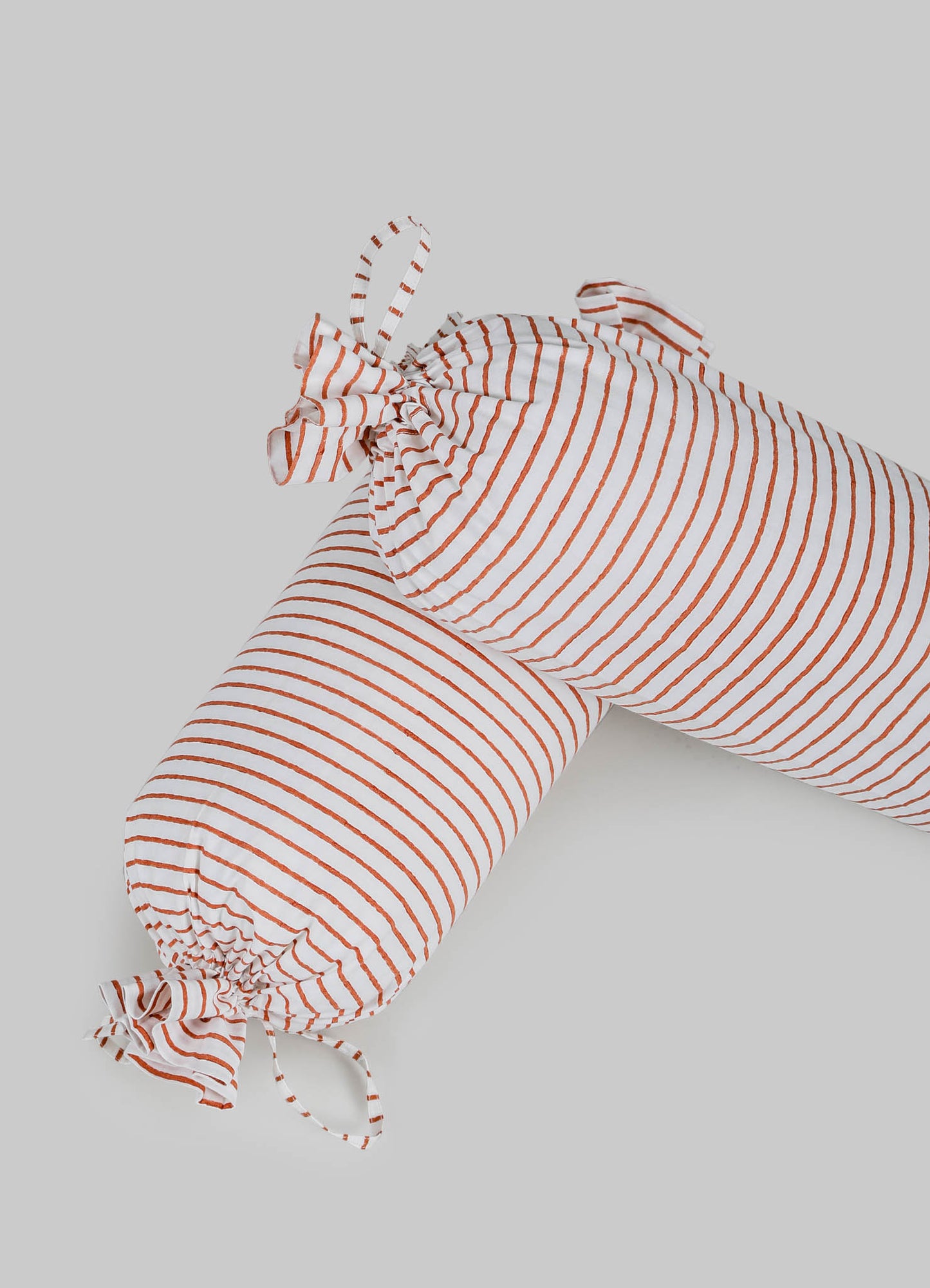 A striped fabric item, likely a cushion cover or textile, made from lightweight material with white and rust-red horizontal lines. It features fabric ties at the corners, creating a gathered effect, in a casual or contemporary style.