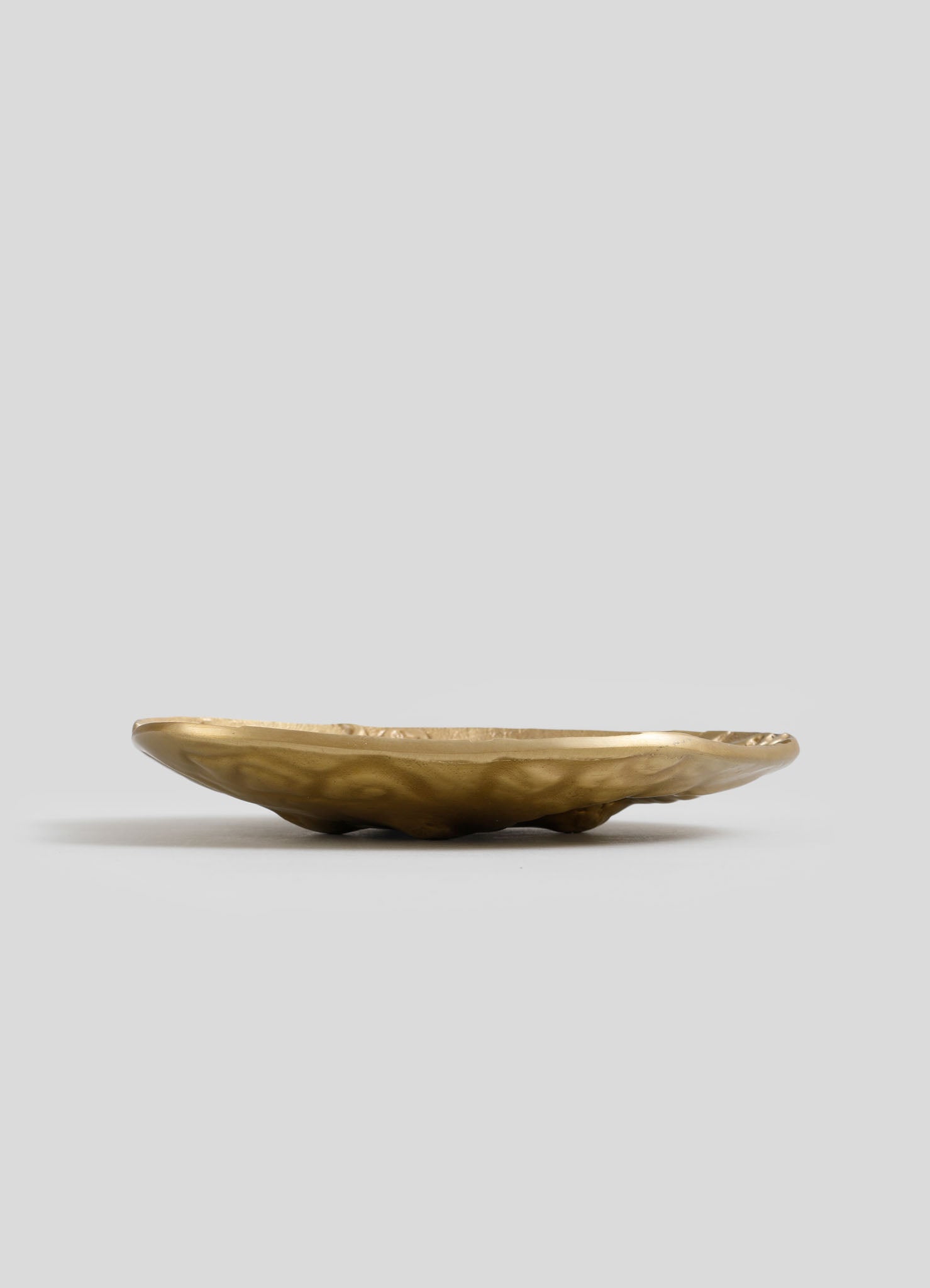 Handcrafted brass bowl with an irregular, organic shape and a polished finish, placed on a neutral background.