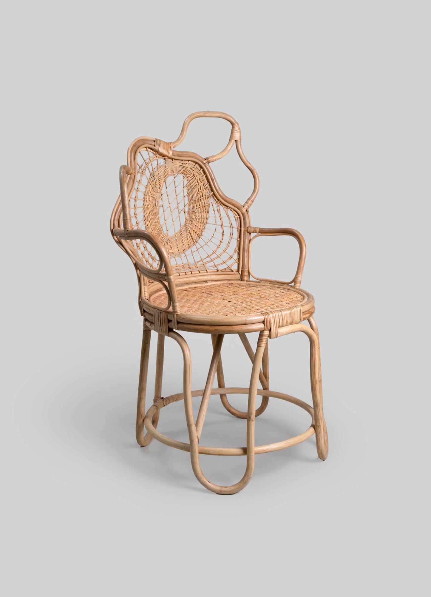 Woven rattan armchair with a high backrest featuring an oval openwork design, rounded armrests, and a circular woven seat, showcasing a handcrafted style. The natural-colored rattan has a smooth finish, and the chair has a curved frame with ergonomic support.