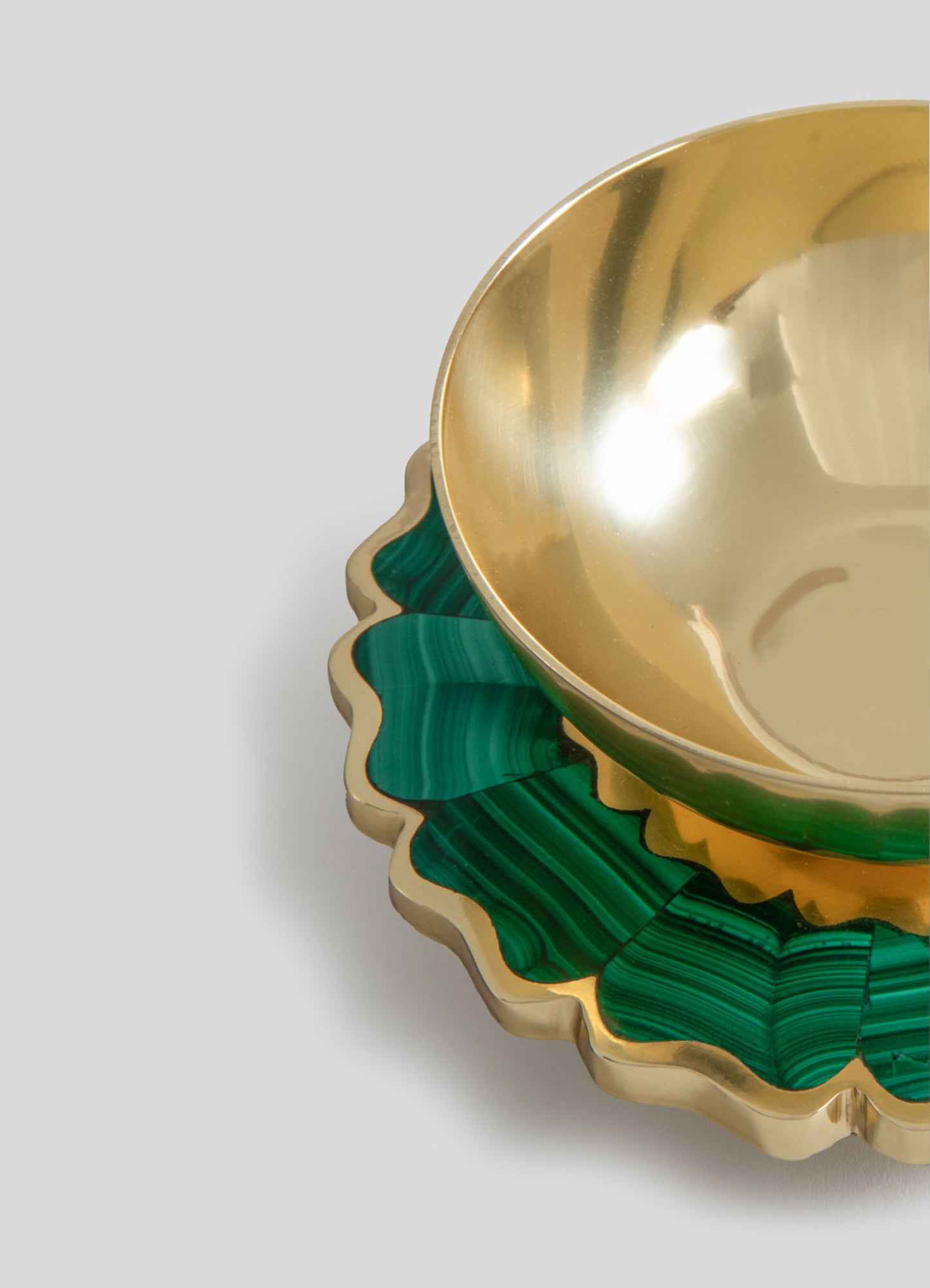 A decorative bowl with a polished gold interior and an ornate scalloped edge featuring green malachite-patterned accents, crafted from metal and stone. The design combines luxury metallic finish with natural motifs.