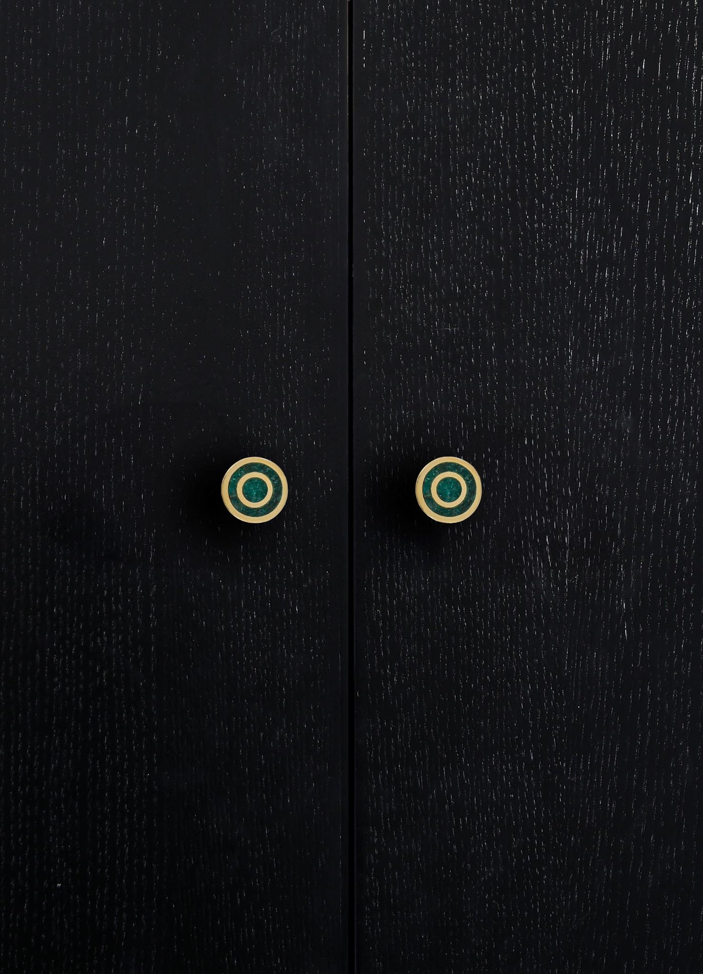 Black wooden cabinet with a textured finish and round, gold-accented drawer handles featuring concentric circles. The design is contemporary with a focus on sleek, minimalist aesthetics.