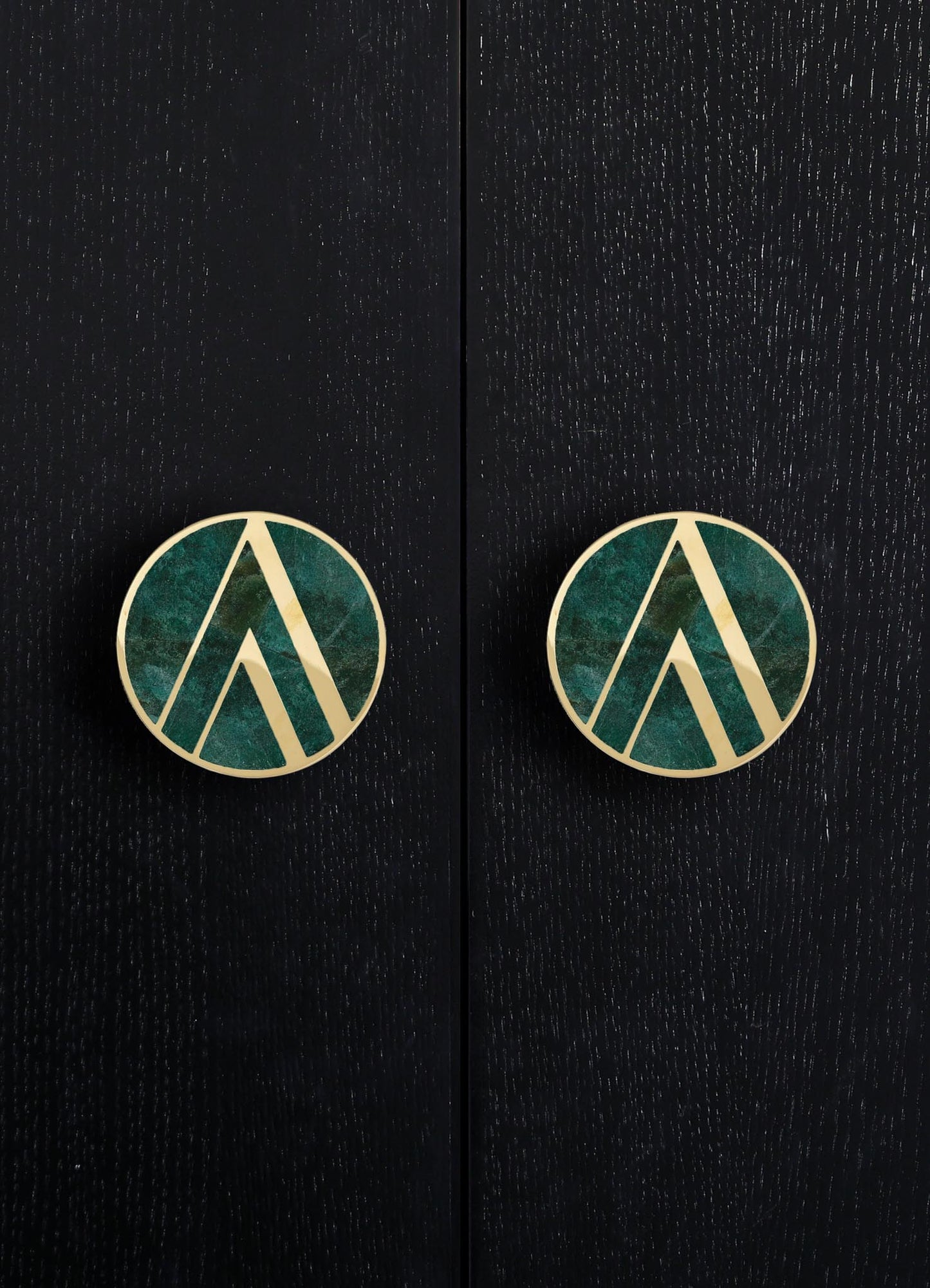 Round earrings featuring a geometric pattern with gold outlines and a green and blue marbled interior, set against a dark, textured background.