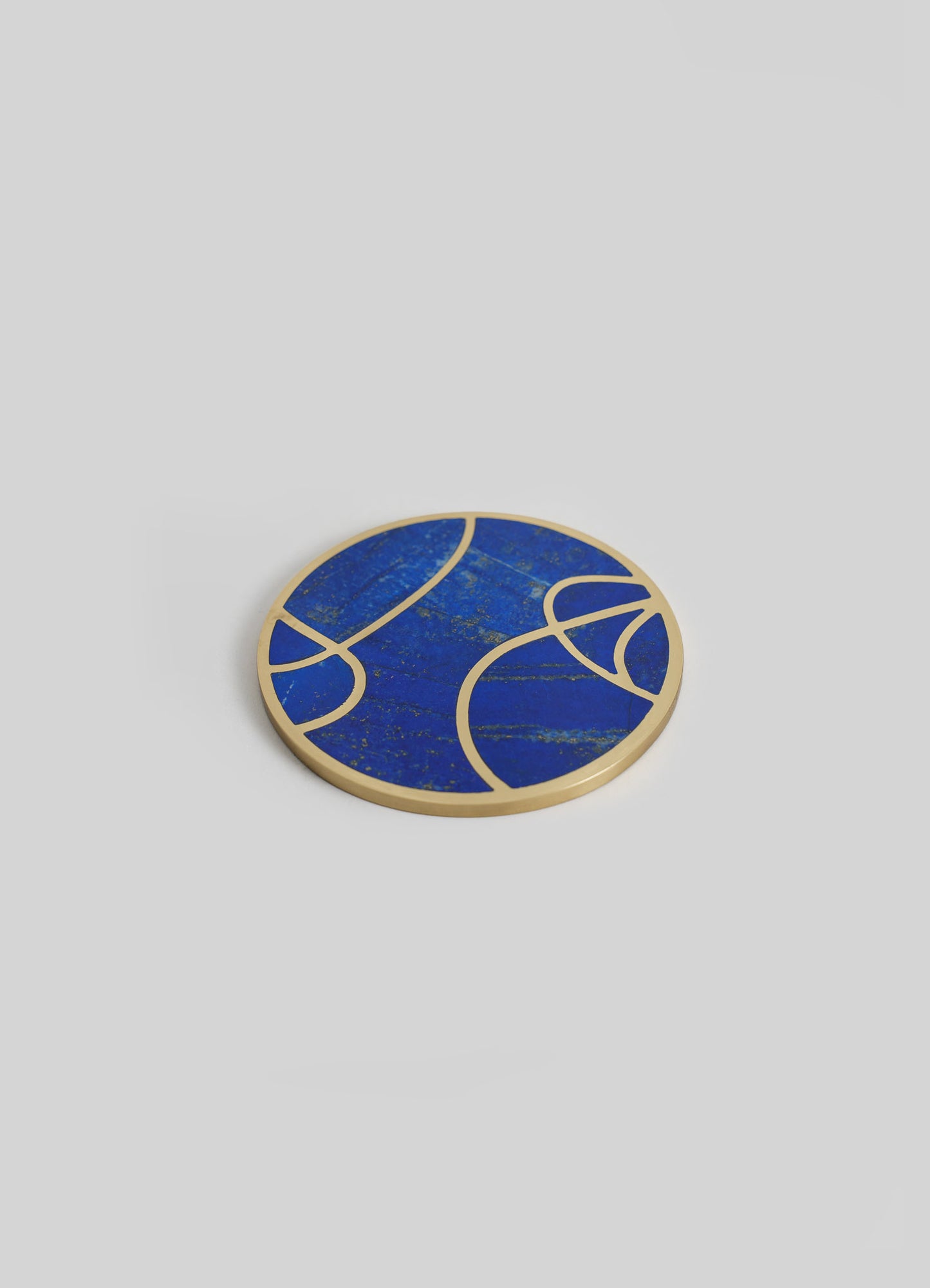 A round decorative tray with a blue marble pattern and gold-colored trim, featuring abstract curved line motifs, placed on a light gray surface.