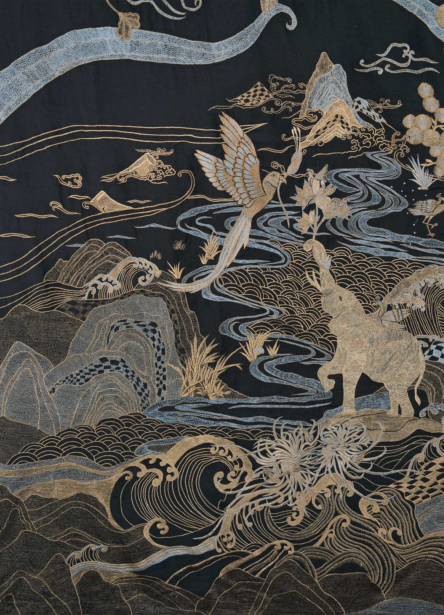 The Dreamscape Black & Gold Embroidered Bedcover by Viya features gold and silver embroidery inspired by Rajput motifs, depicting a fantasy landscape with swirling water, clouds, mountains, a crane, a deer, and stylized foliage on a dark base.