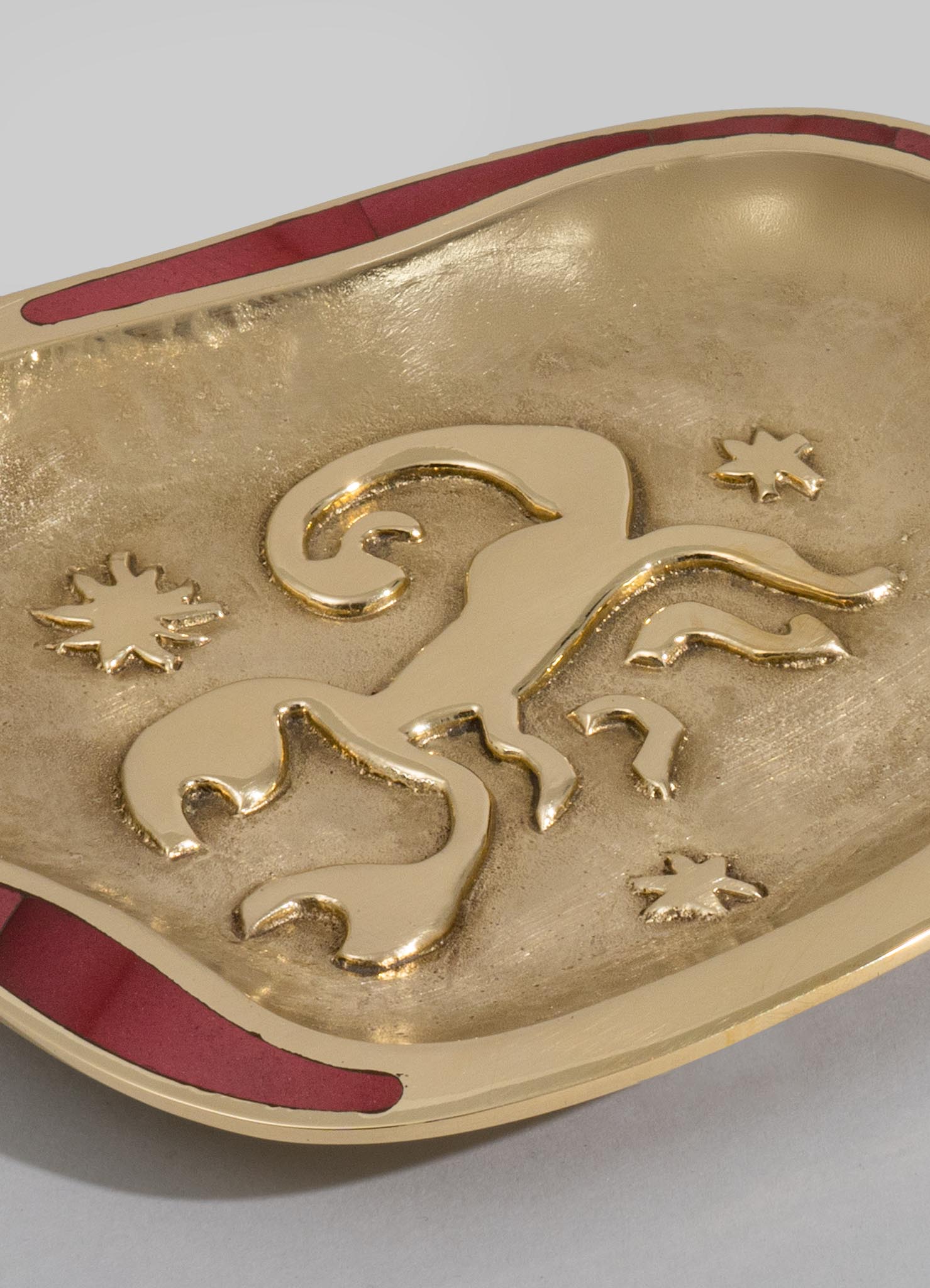 A decorative ceramic dish featuring a gold finish with an embossed unicorn motif and small star patterns, accented with red trim along the edge. The style appears handcrafted with a whimsical, fantasy-inspired theme.