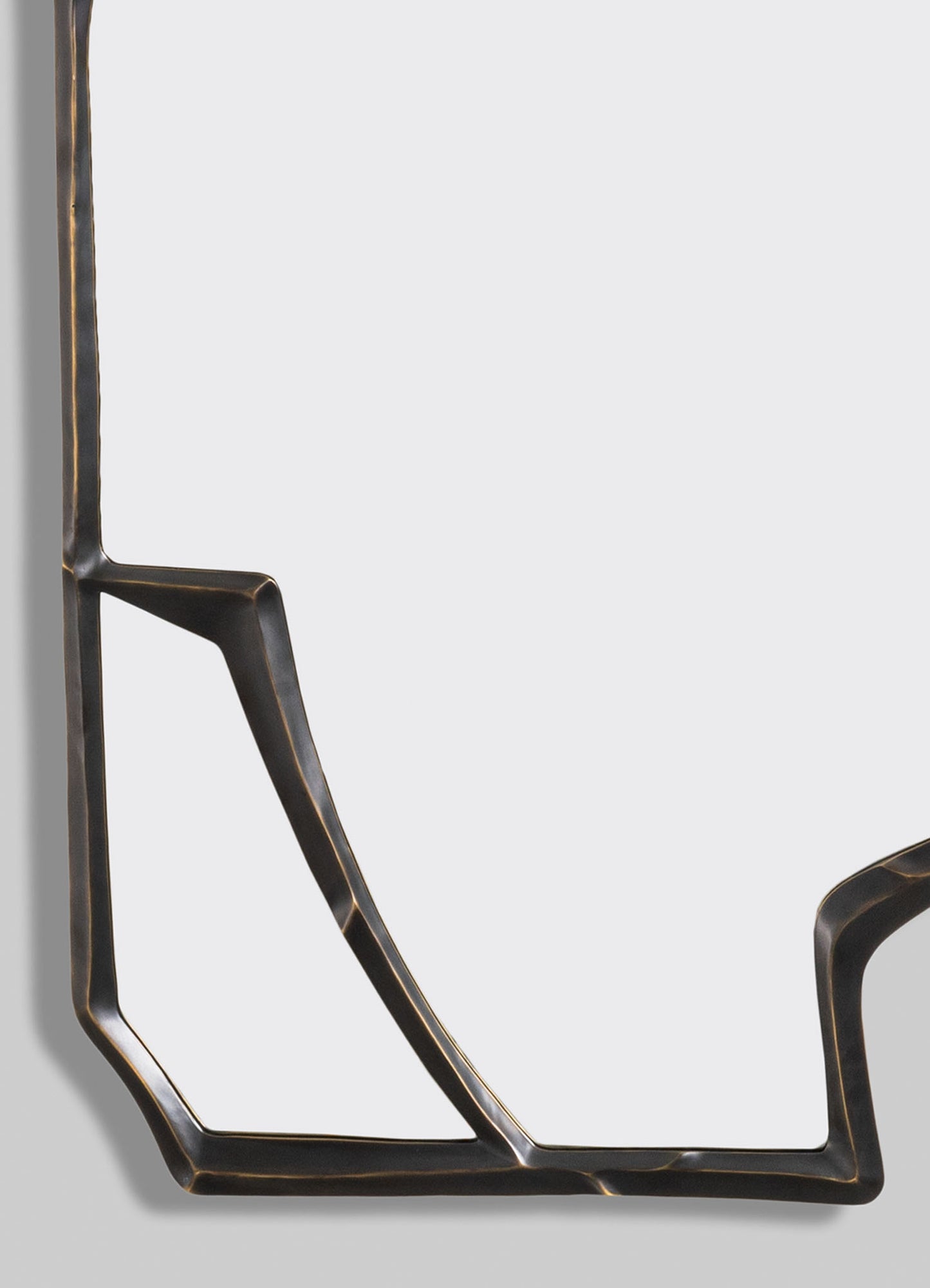 A decorative mirror with a geometric metal frame in black finish with brass accents, featuring angular lines and a contemporary style.