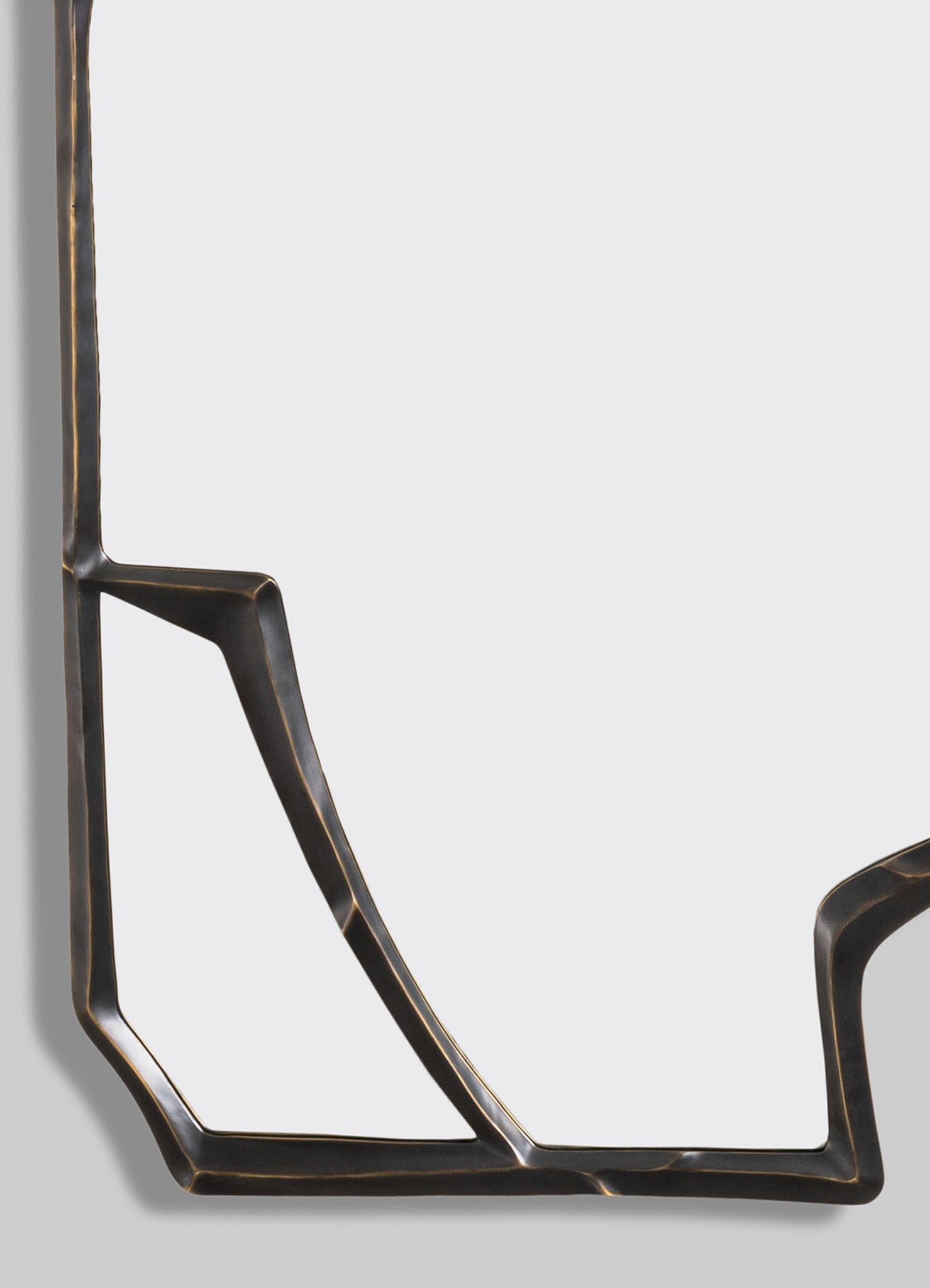 A decorative mirror with a geometric metal frame in black finish with brass accents, featuring angular lines and a contemporary style.