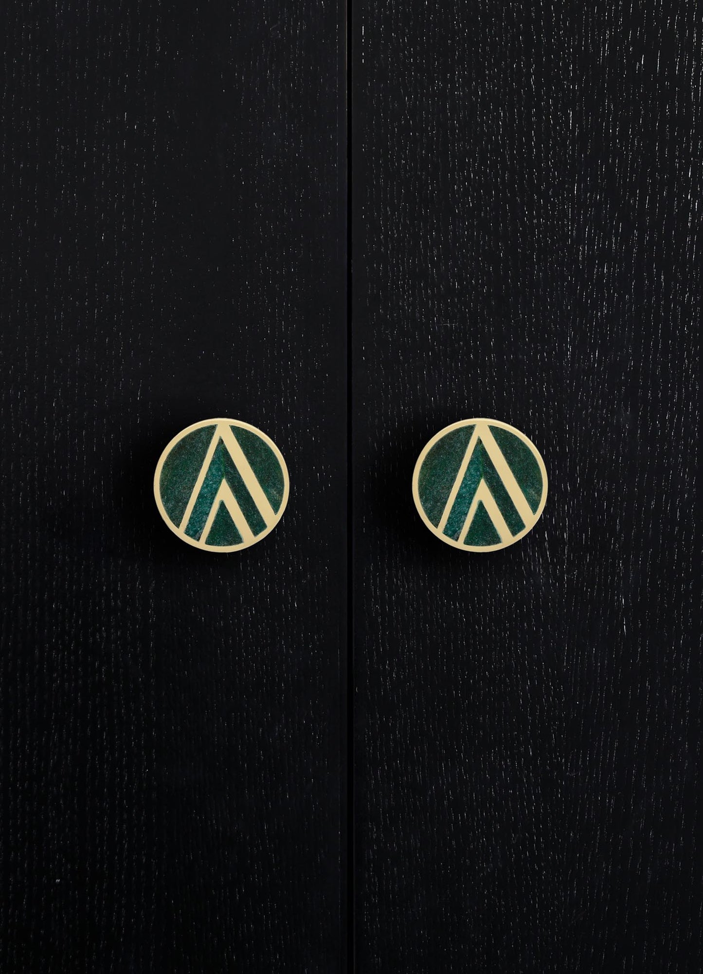 Black wooden furniture with a textured finish featuring two round brass knobs with geometric teal and cream motifs. The style is contemporary with a focus on sleek lines and distinctive hardware details.