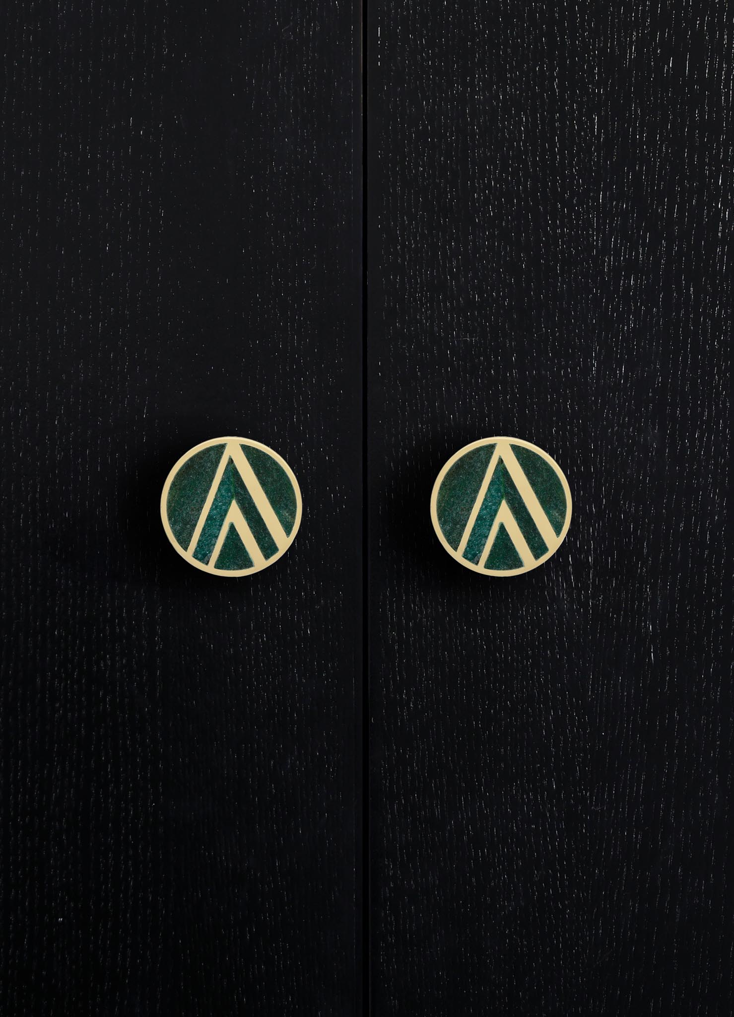 Black wooden furniture with a textured finish featuring two round brass knobs with geometric teal and cream motifs. The style is contemporary with a focus on sleek lines and distinctive hardware details.