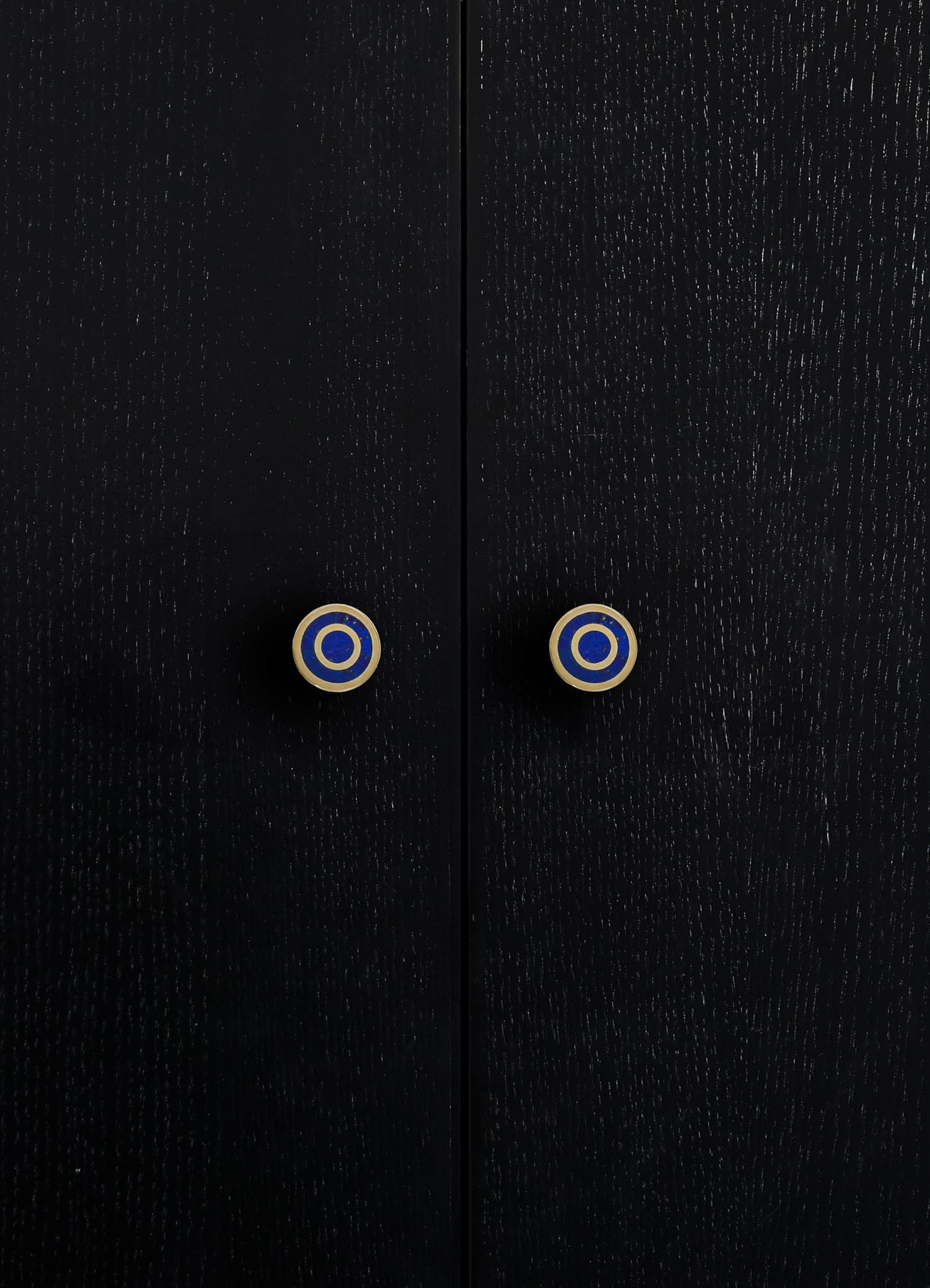 Close-up of black wooden furniture with a textured finish and round ceramic knobs featuring blue, white, and gold concentric circles.