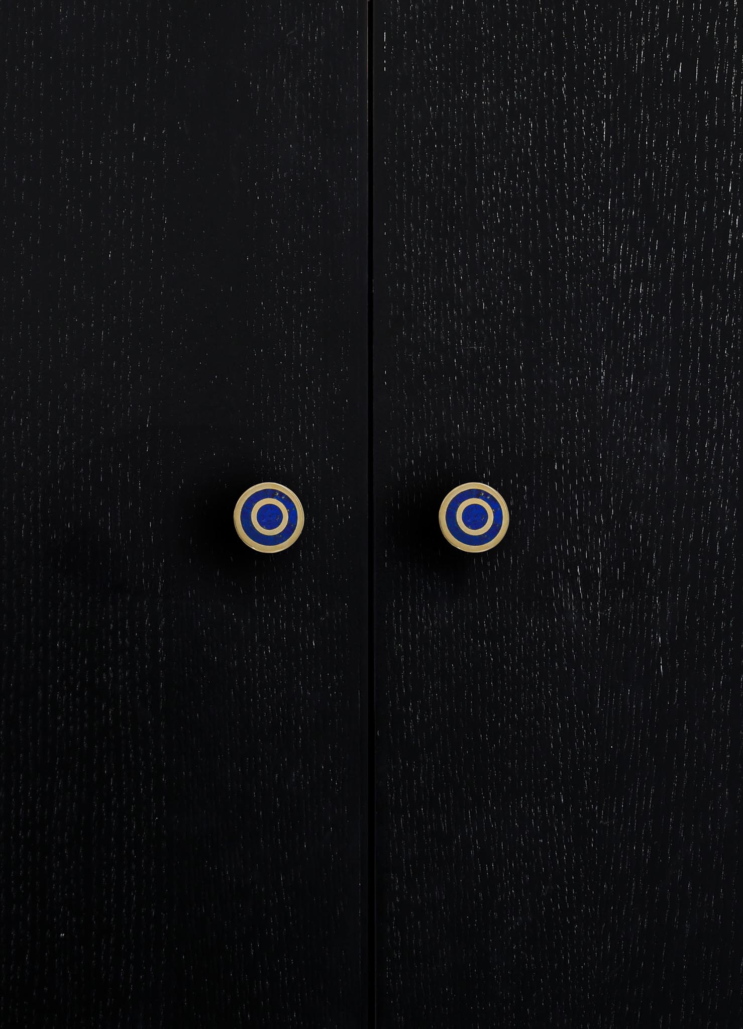 Close-up of black wooden furniture with a textured finish and round ceramic knobs featuring blue, white, and gold concentric circles.