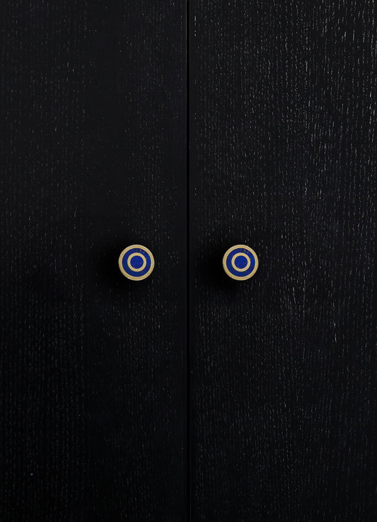 Close-up of black wooden furniture with a textured finish and round ceramic knobs featuring blue, white, and gold concentric circles.