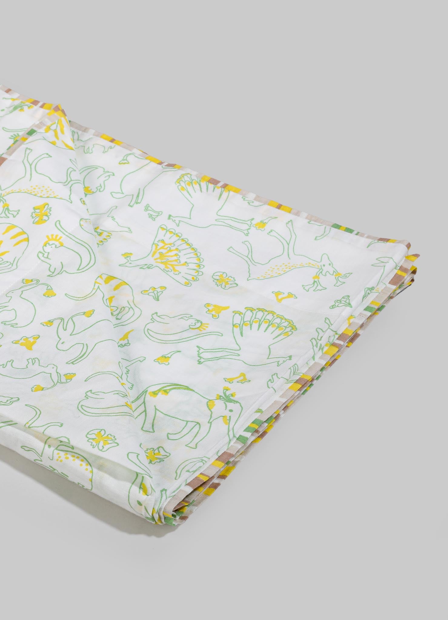 Cotton tablecloth with a playful yellow and green animal print featuring elephants and peacocks, bordered with a multicolored striped pattern.