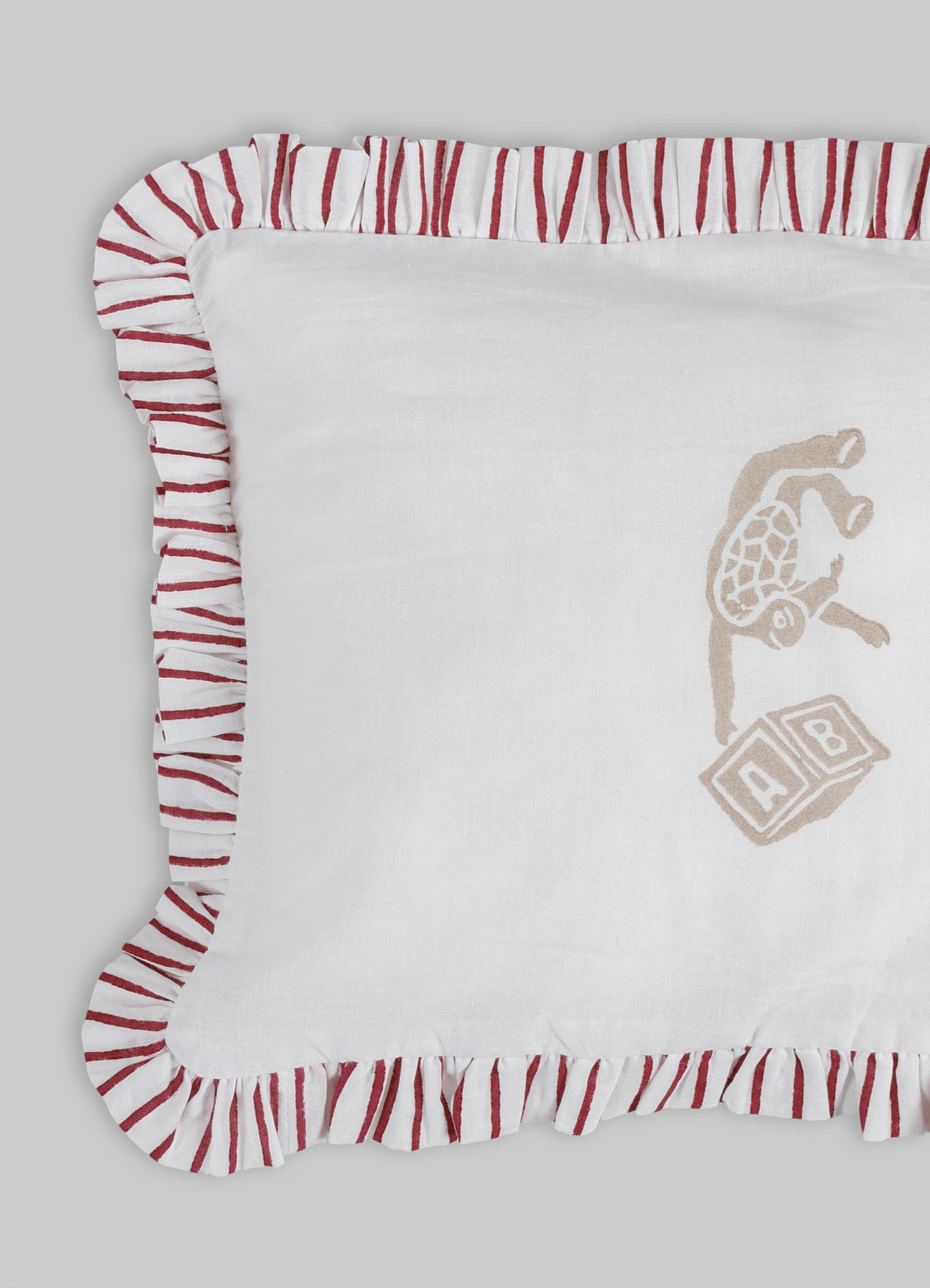 Baby crib bedding set featuring a white fabric with embroidered animal and block motifs in beige and light brown, with a ruffled trim in red and white stripes. Made of soft cotton or linen material, designed for a cozy nursery setting.