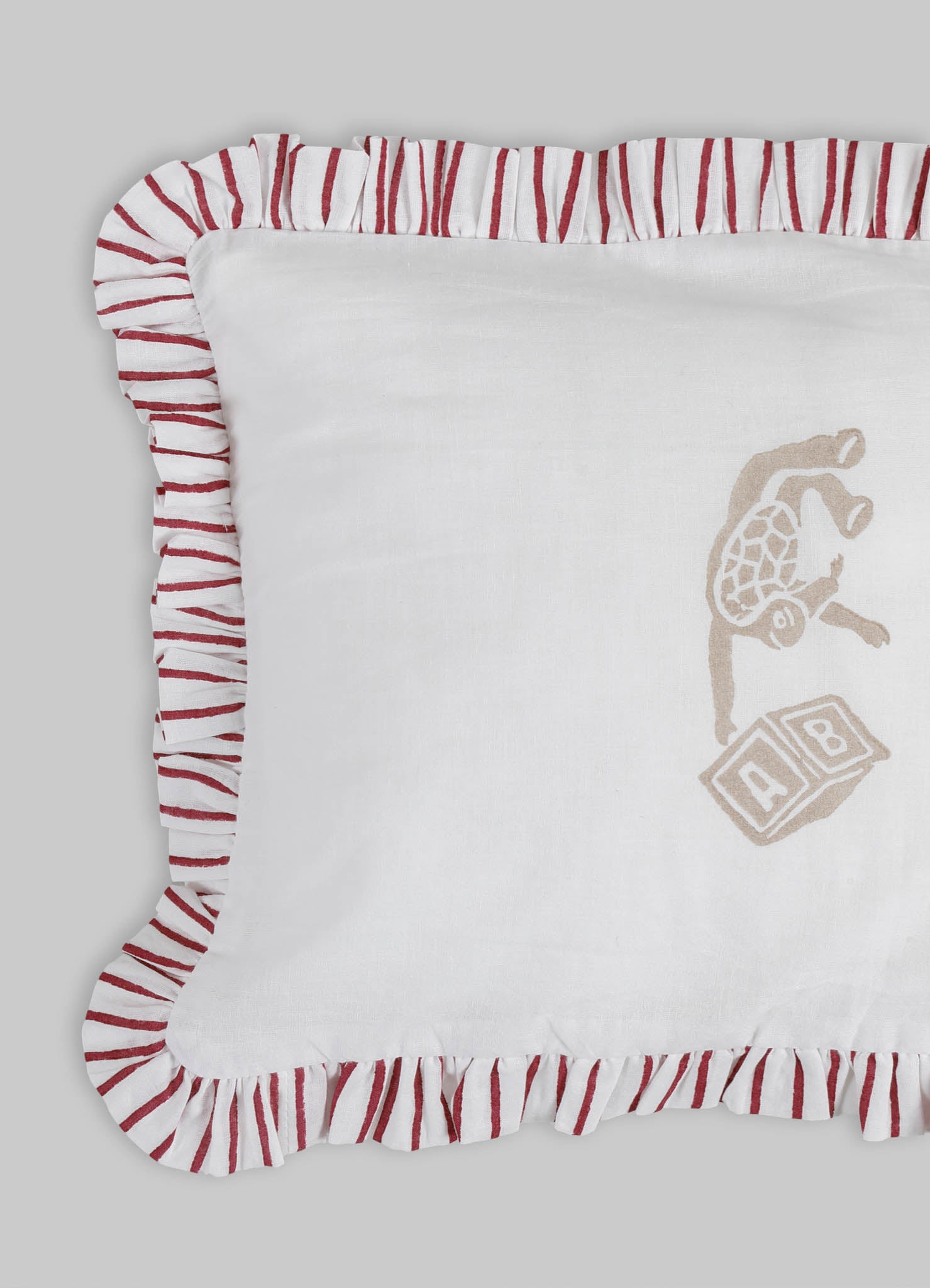 Baby crib bedding set featuring a white fabric with embroidered animal and block motifs in beige and light brown, with a ruffled trim in red and white stripes. Made of soft cotton or linen material, designed for a cozy nursery setting.