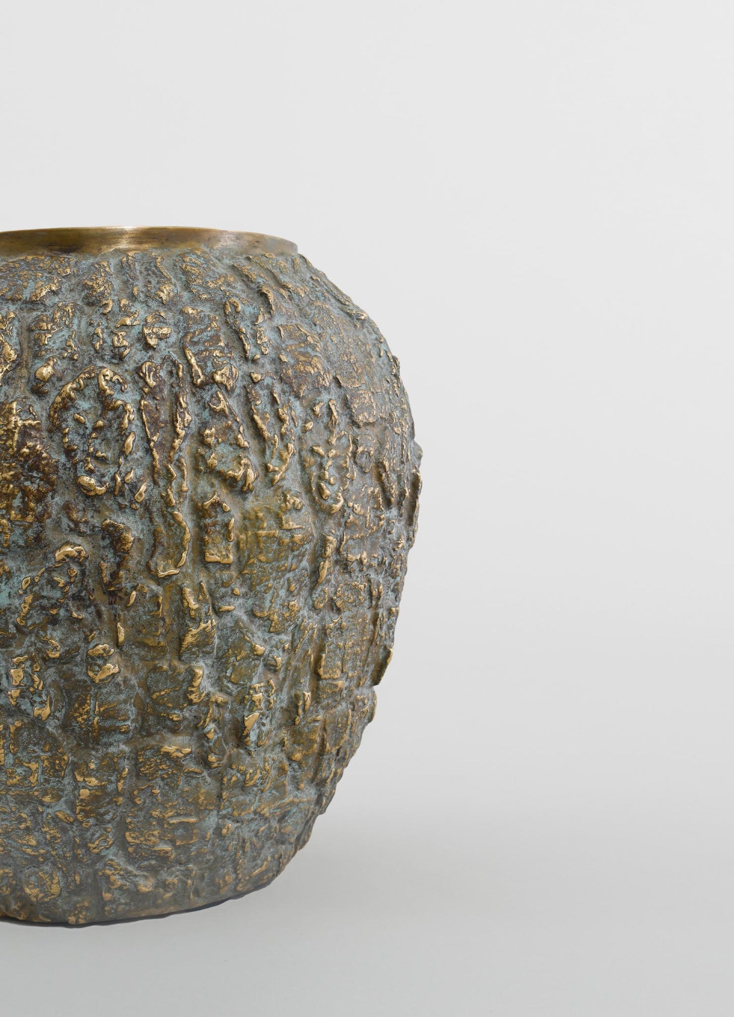A textured metallic vase with an aged, distressed finish in shades of bronze and gold. The vase has a rounded shape with a rough, uneven surface pattern that enhances its rustic, handcrafted style.
