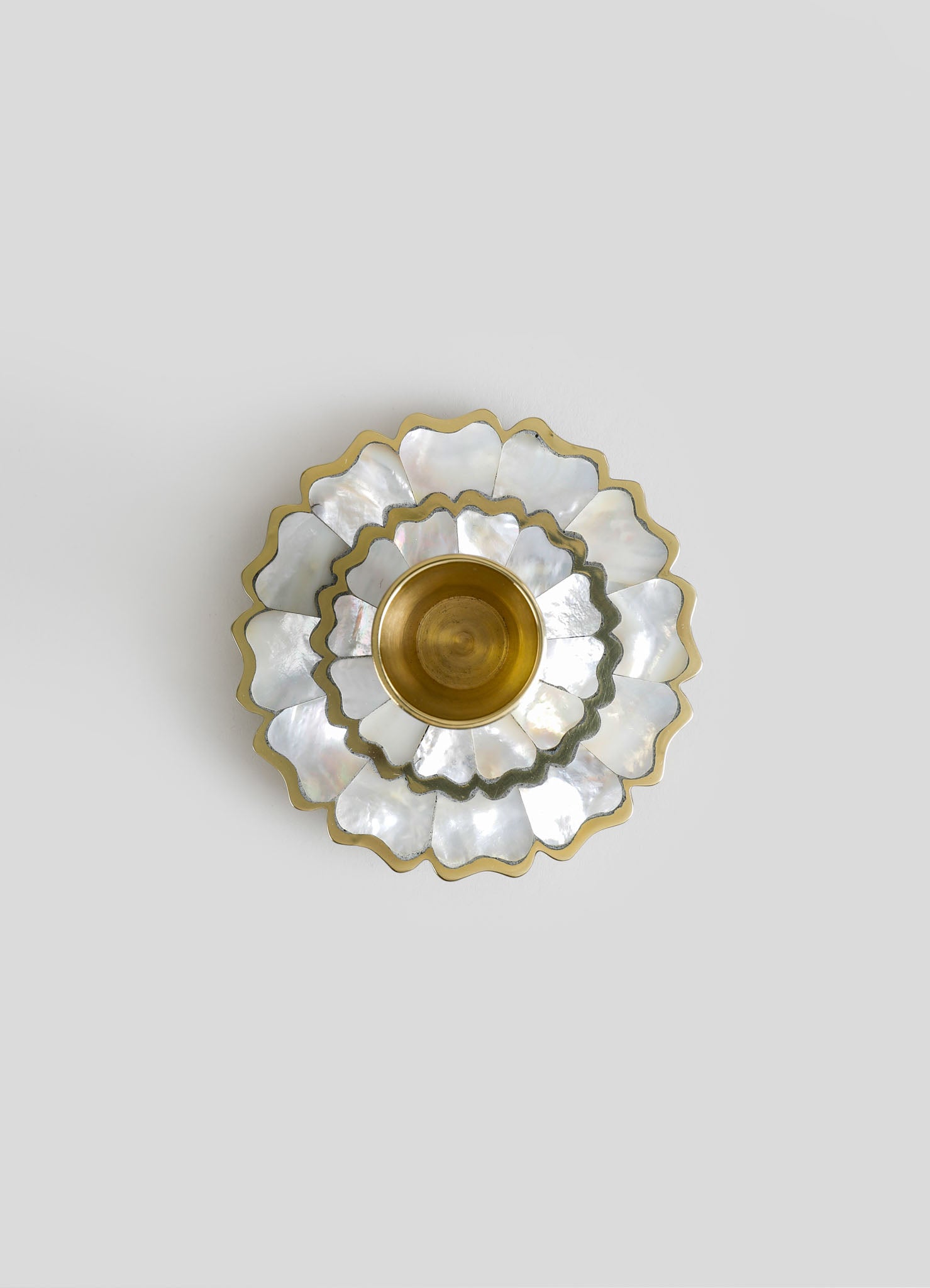 Decorative wall-mounted piece with layered scalloped shapes made of iridescent mother-of-pearl and brass, arranged in a floral motif with a metallic gold finish.
