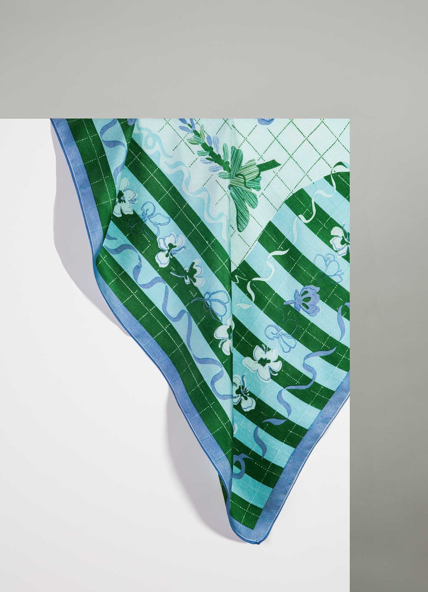 Colorful silk scarf with a floral and plaid pattern in shades of green, blue, and white, featuring decorative borders and delicate line detailing. The fabric appears smooth and lightweight, with a refined, classic style.