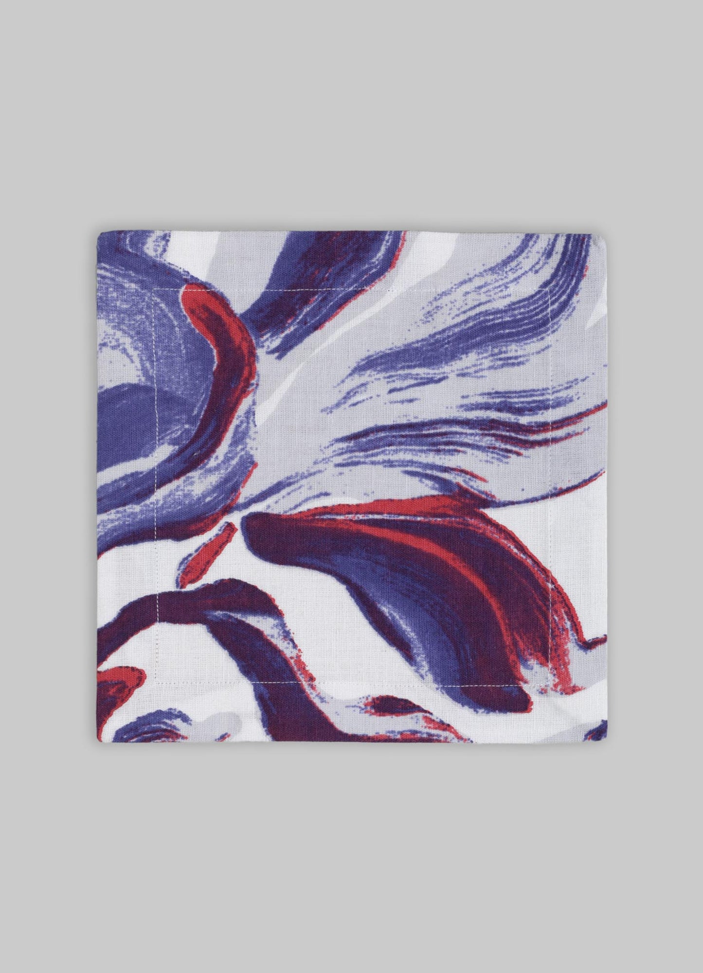 Printed fabric napkin with an abstract floral pattern in shades of blue, red, and white on a grey background.
