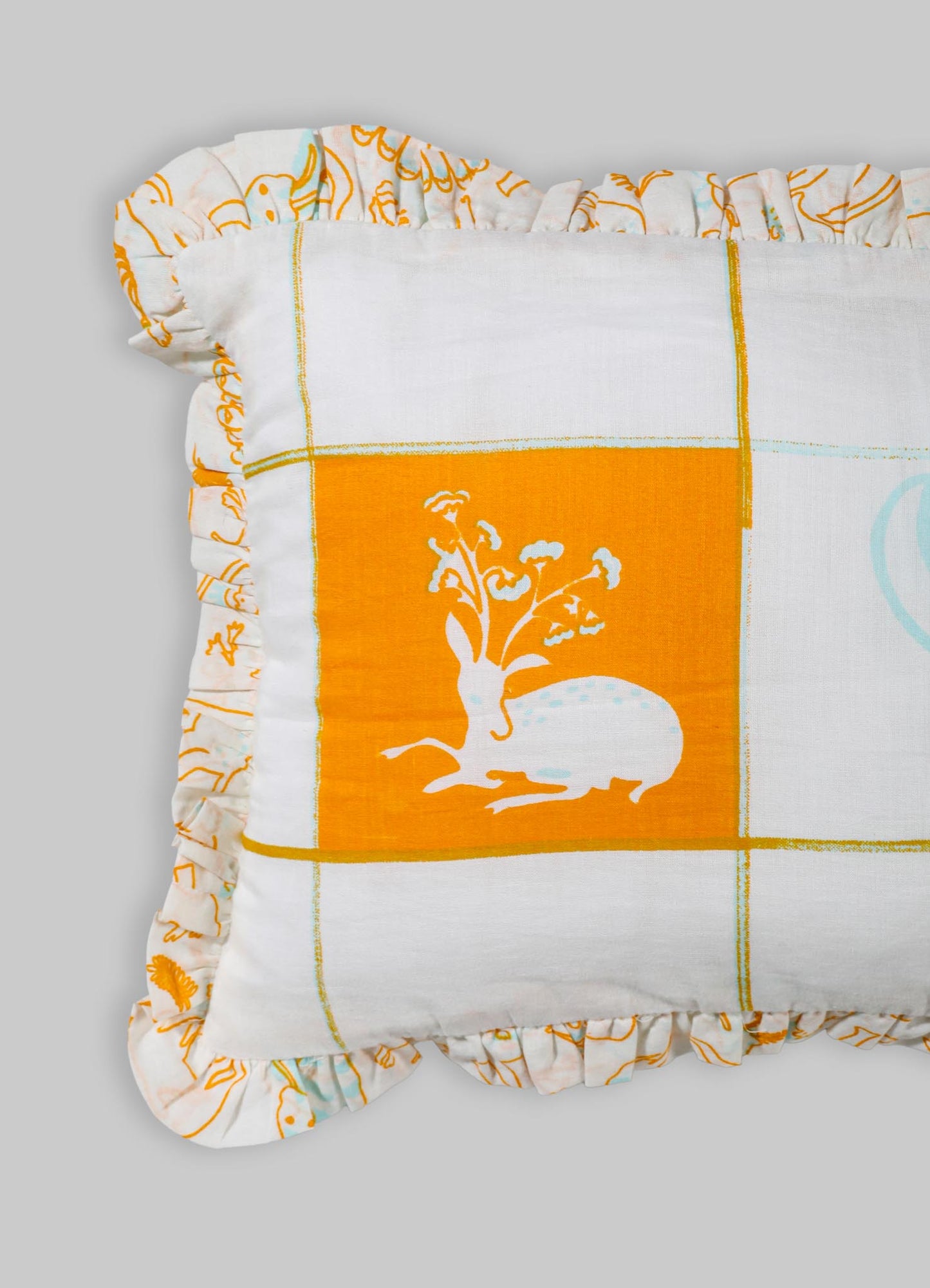 A decorative cushion cover made of cotton fabric with an orange and white color palette, featuring a floral motif and a ruffled edge. The design includes a grid pattern with a central floral illustration on a solid orange background.