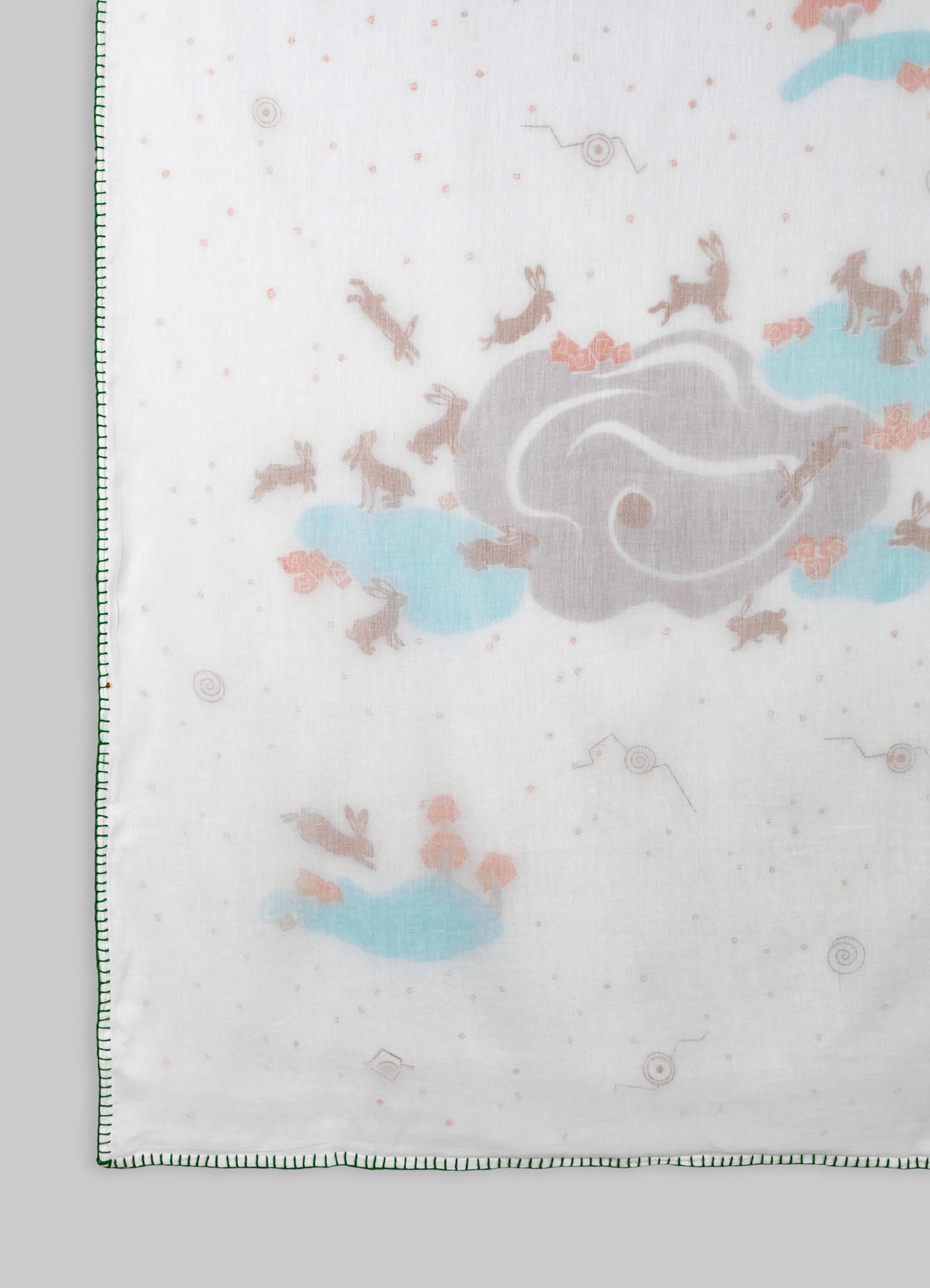Soft cotton or linen fabric with a whimsical printed design featuring rabbits, clouds, and abstract motifs in pastel shades of pink, blue, and beige. The fabric has a neatly stitched green embroidered border, creating a playful and delicate aesthetic suitable for children's bedding or decorative textiles.