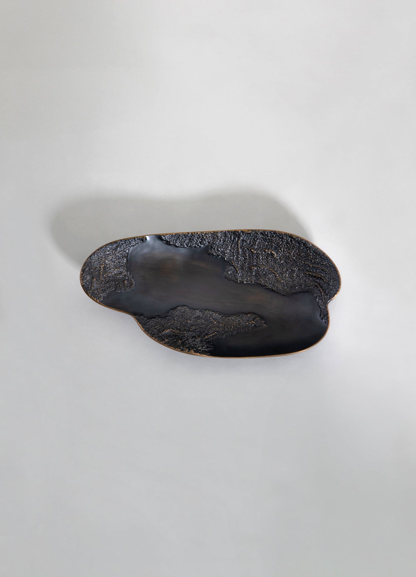 A black and gold textured ceramic tray with an elongated oval shape, featuring a glossy black center and intricate gold accents along the edges, set against a plain white background.